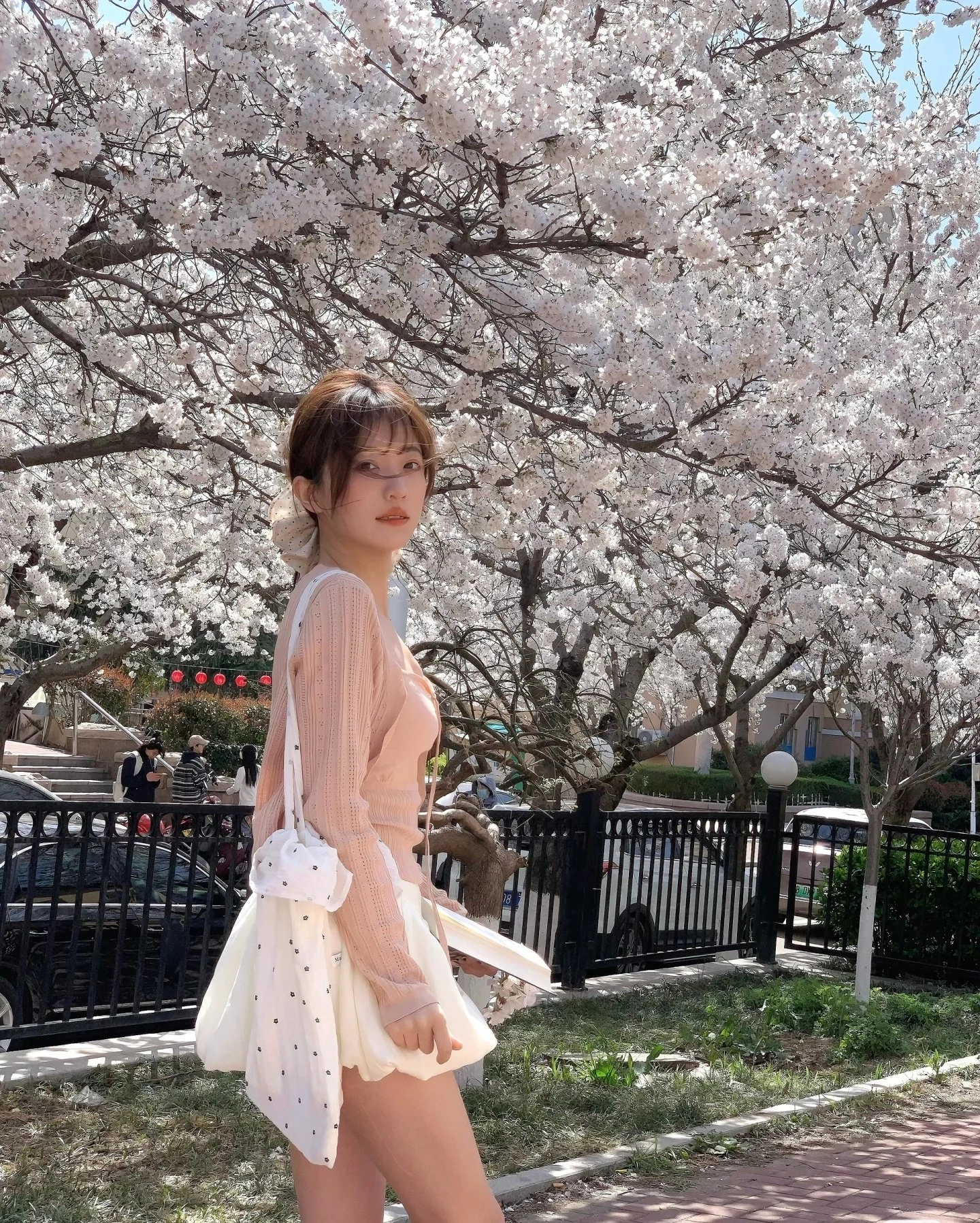 穿白衣的女人站在一棵树前。