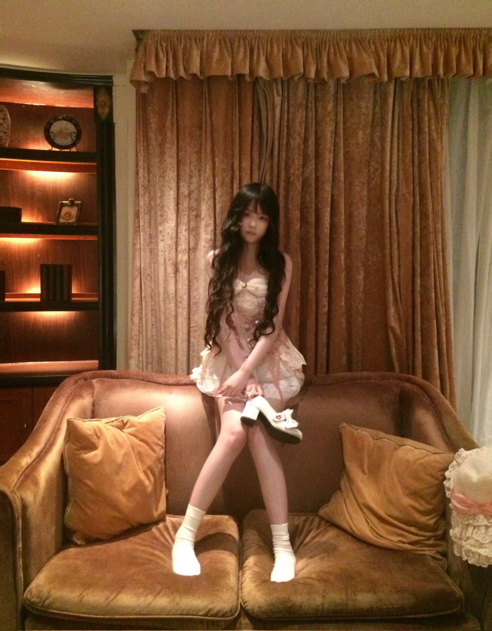 穿着白色裙子和白袜子的女人坐在沙发上。