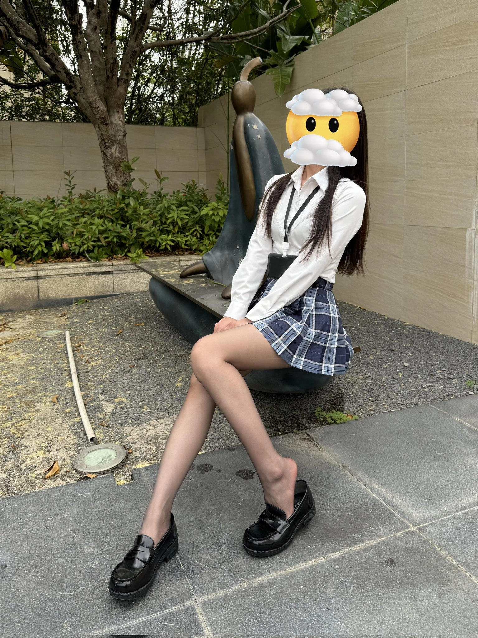 一位穿着黑色衬衫和白色裙子的女人坐在凳子上。