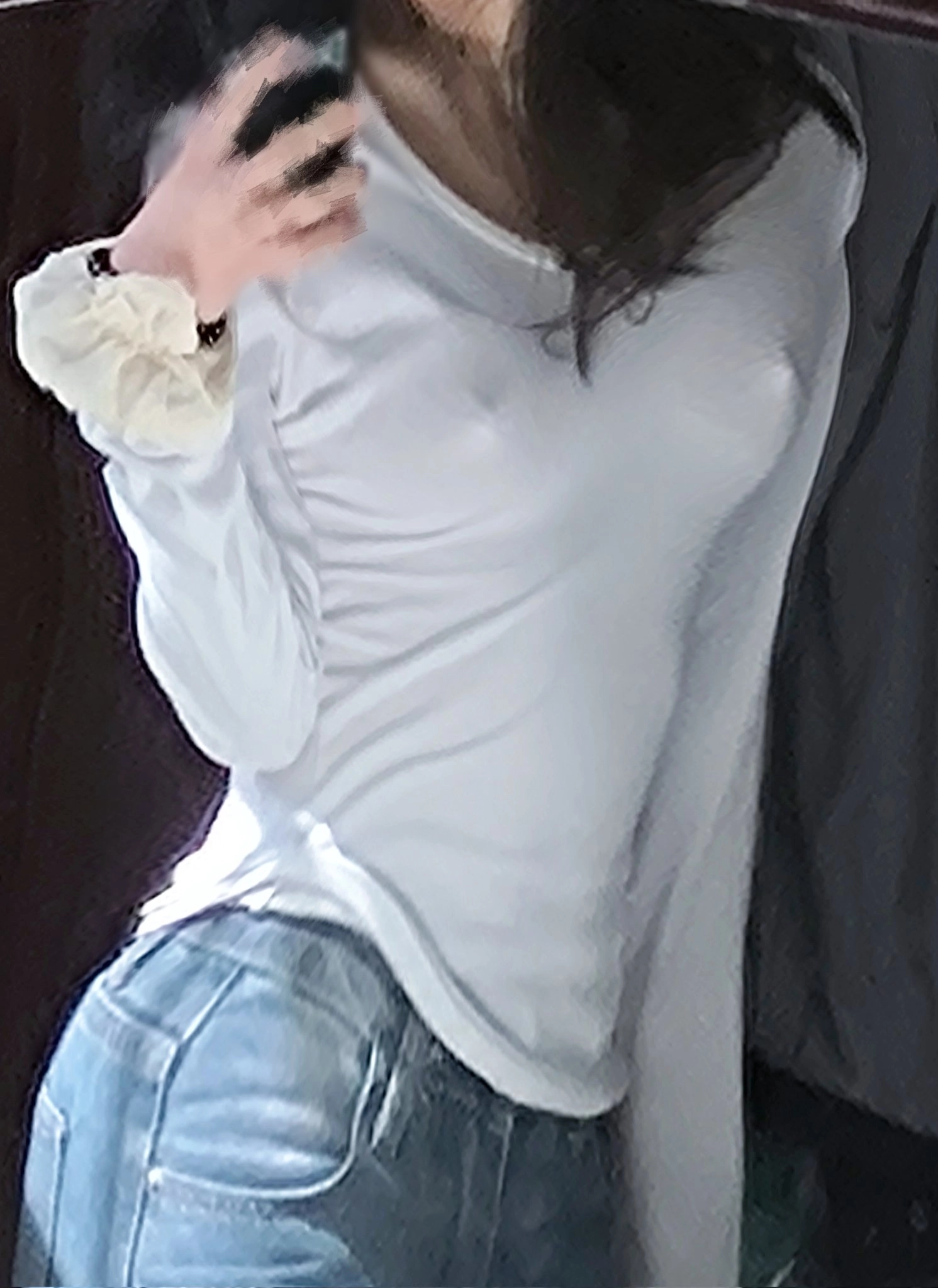 一位穿着白色衬衫和蓝色牛仔裤的女人拿着手机。