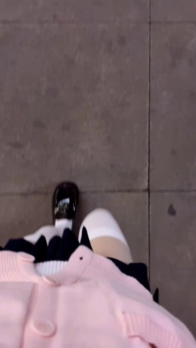 一位穿着粉红色的衬衫和黑色的鞋子的女人在走廊上行走。