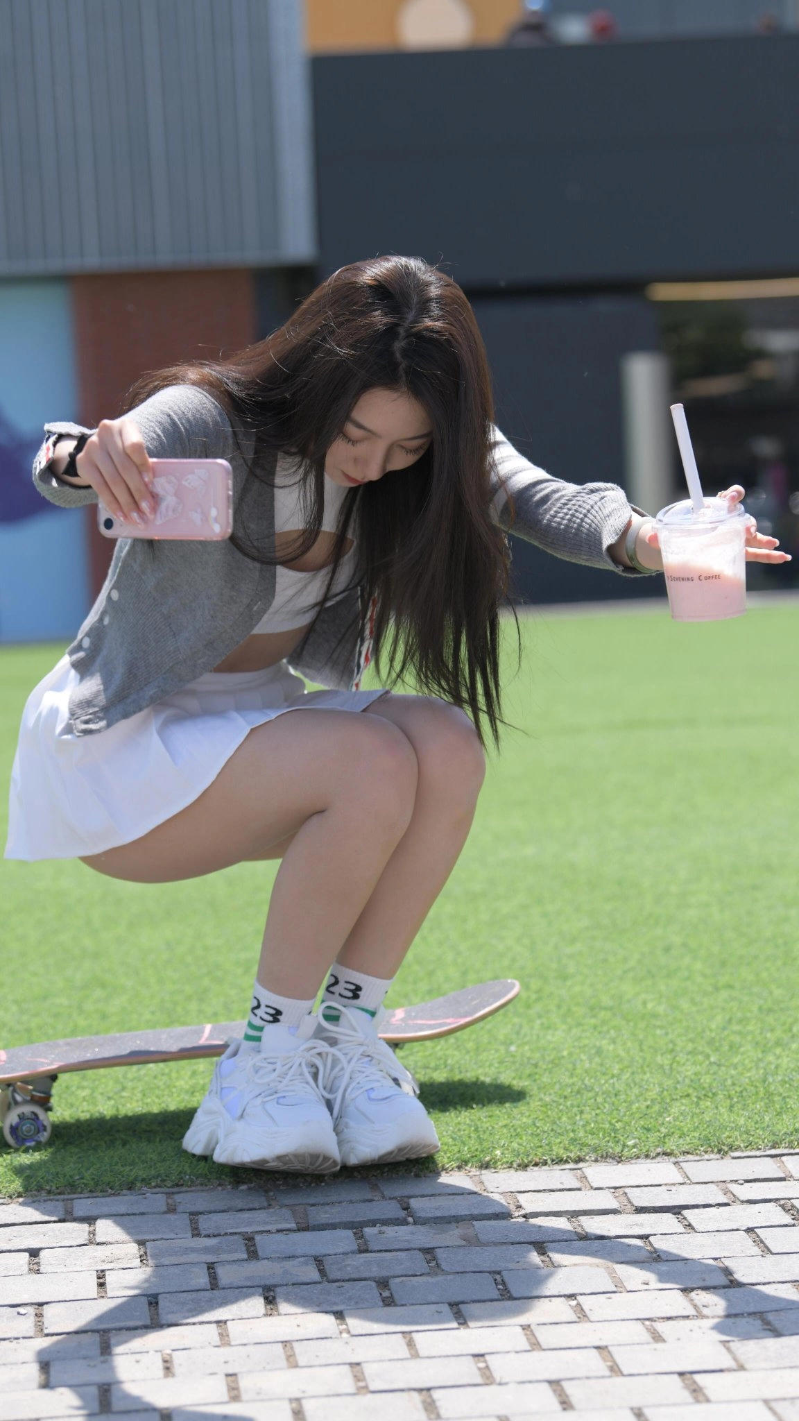 一名女孩在滑板上跪下时拍照她的手机。