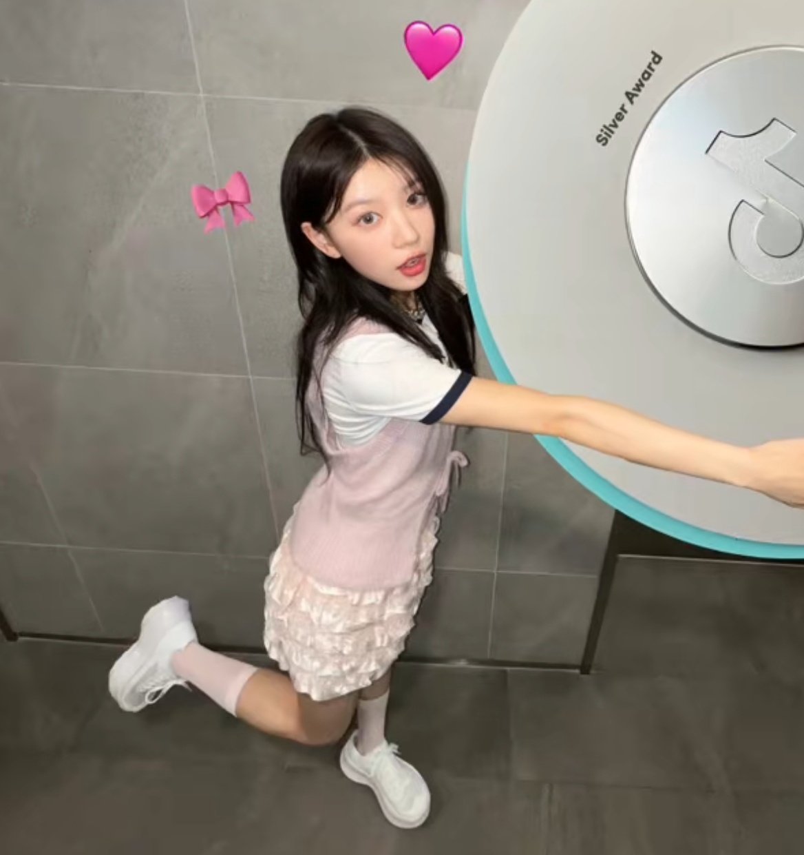 一位穿着粉红色的裙子和白色的鞋子的女孩站在一台机器前面。