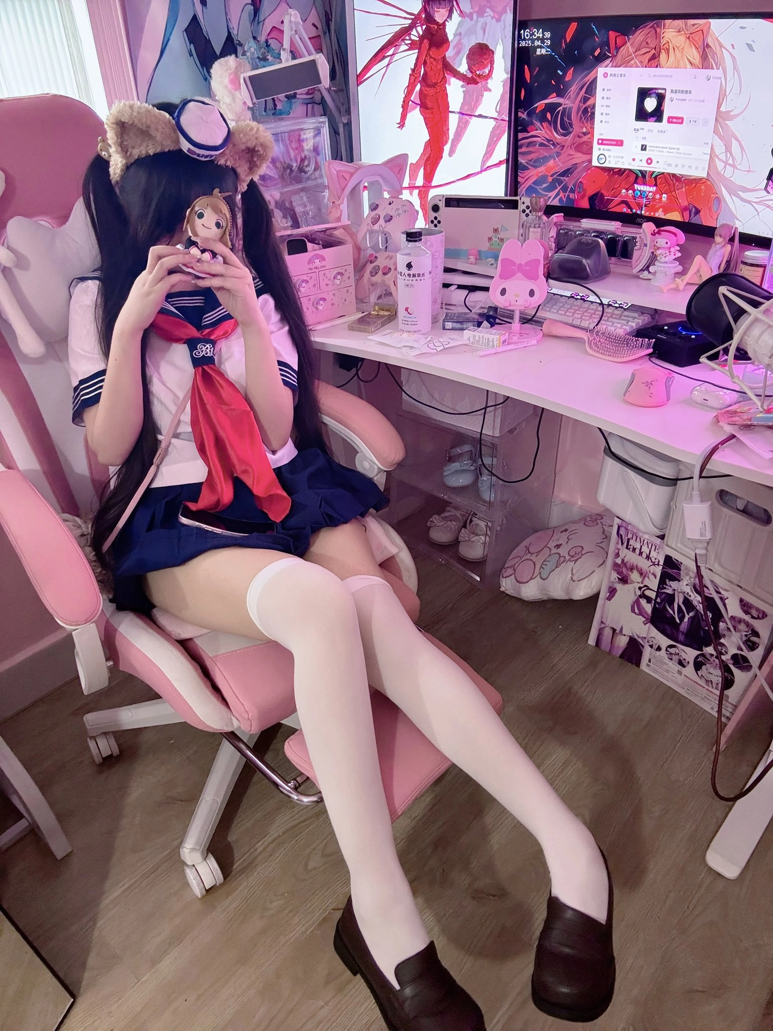 穿着水手服的女孩坐在粉红色的椅子上。