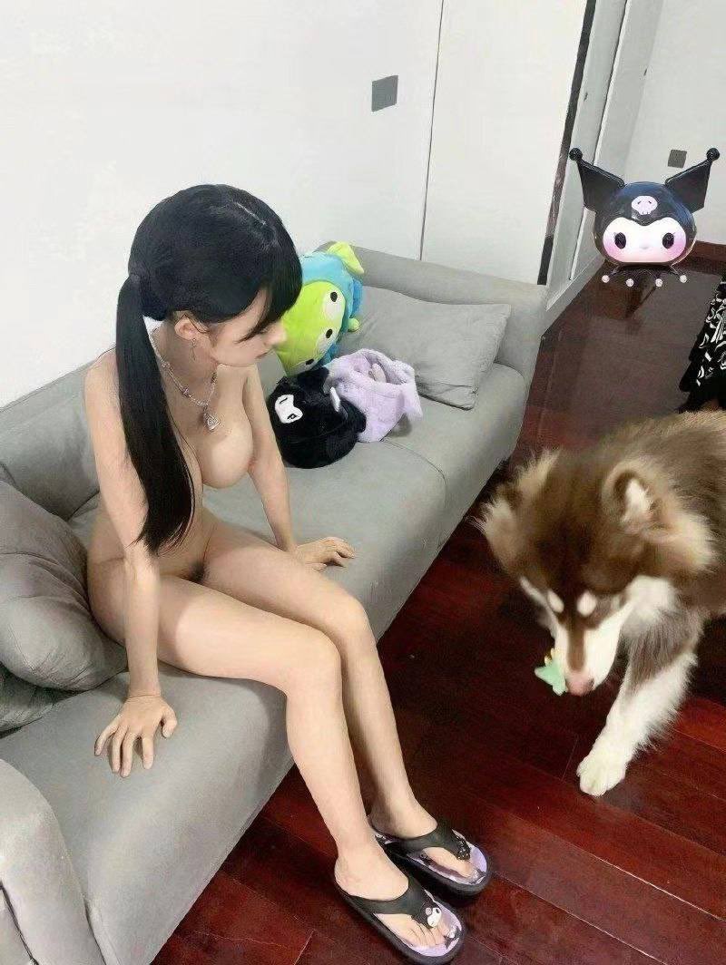 裸体的女人坐在沙发上和一个狗。