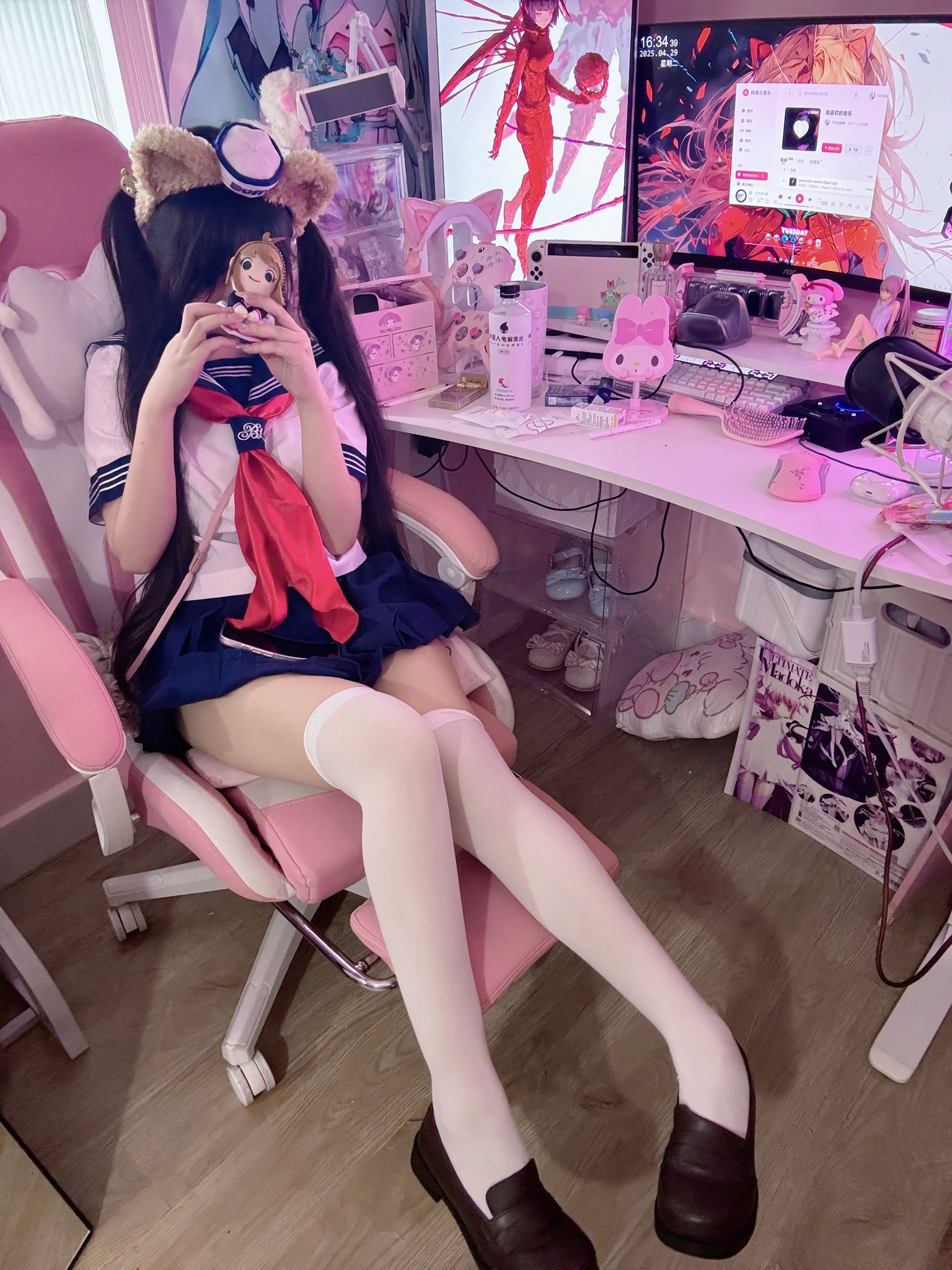 穿着水手服的女孩坐在粉红色的椅子上。