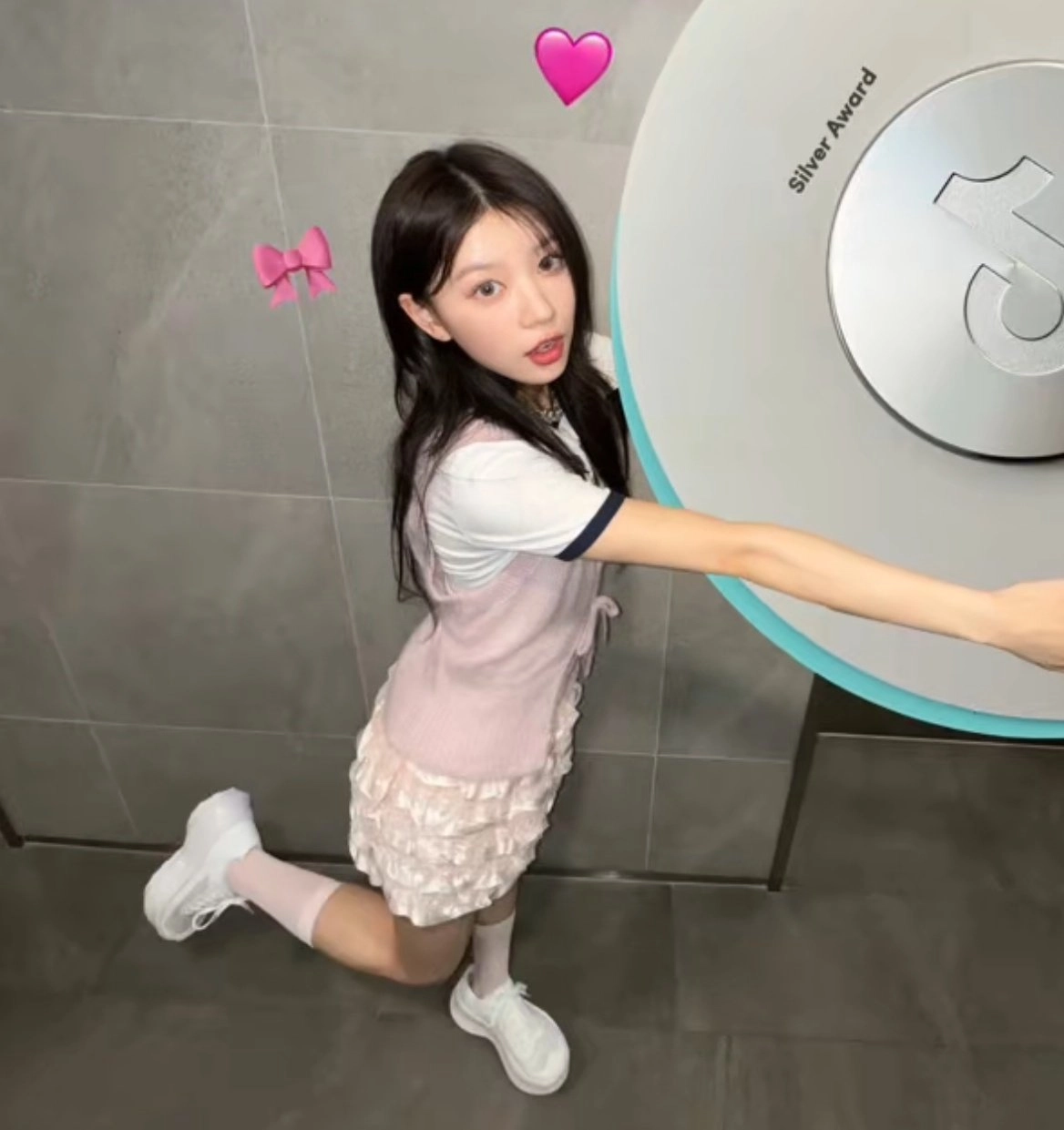 一位穿着粉红色的裙子和白色的鞋子的女孩站在一台机器前面。