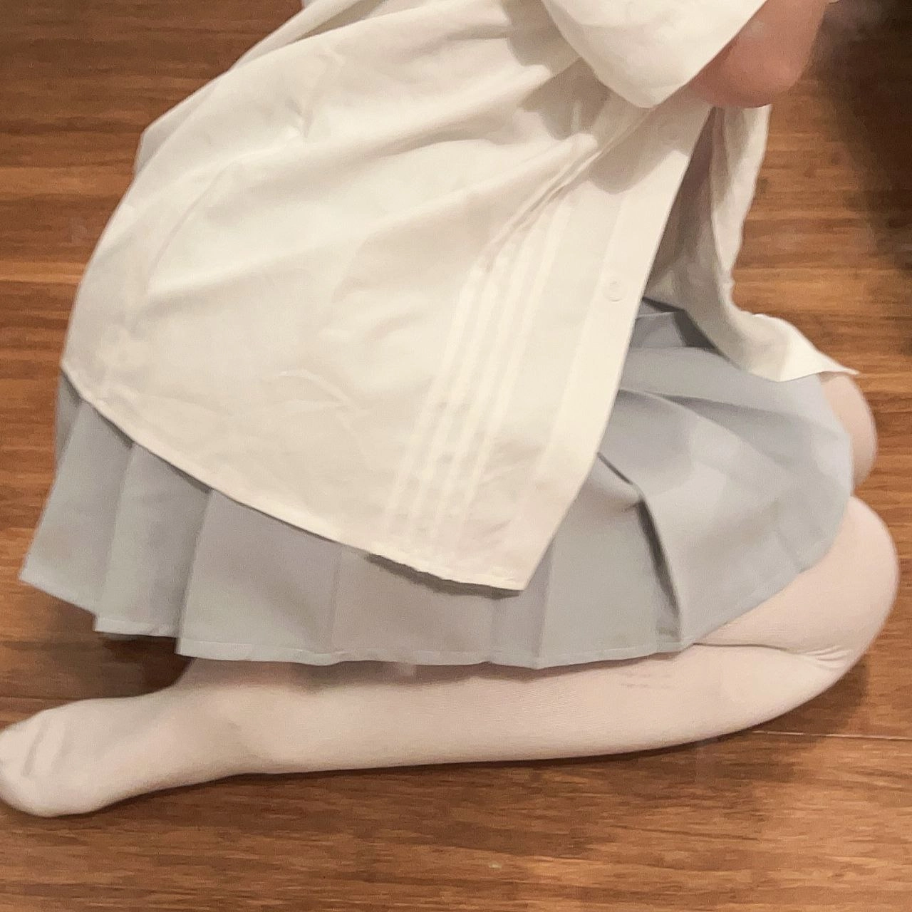 穿着白色衬衫和蓝色裙子的女人跪在地板上。