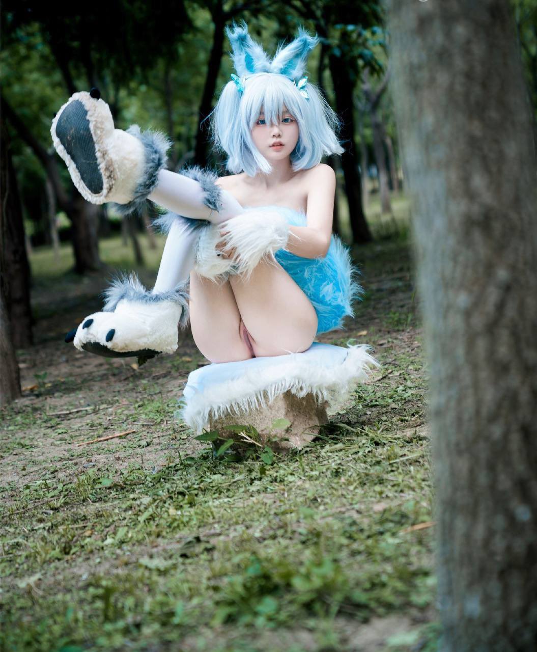 蓝头发和蓝裙子的女人站在一棵树前。