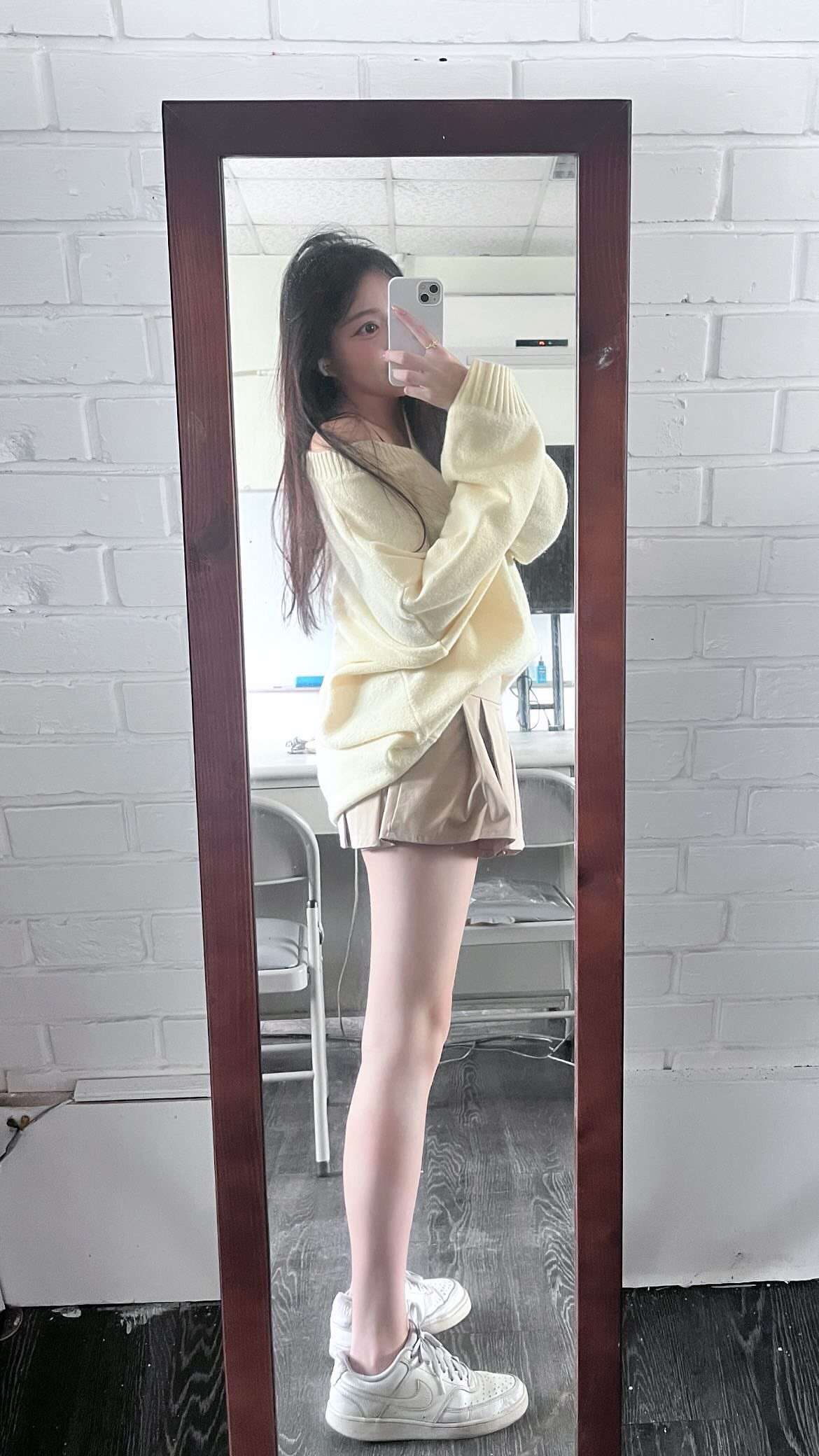 一位穿着白色衬衫和蓝色短裤的女人拿着一杯酒,站在走廊上。