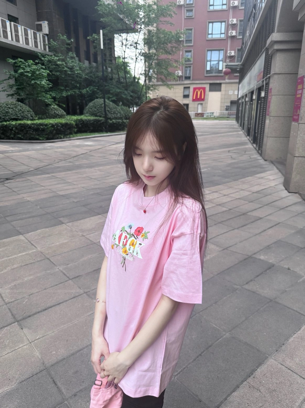 一位穿着粉红色的衬衫和花朵设计的女人站在走廊上。