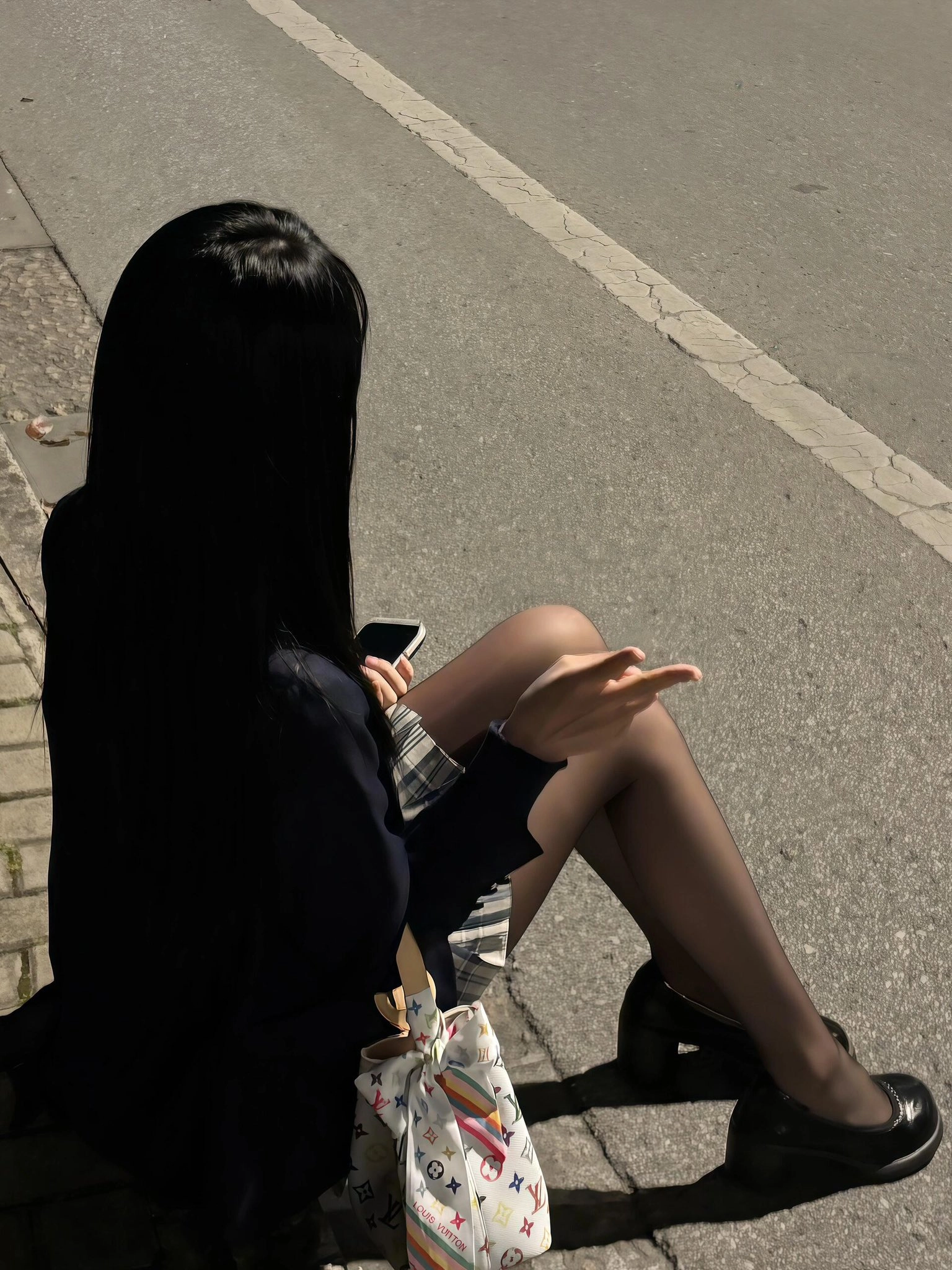 女人坐在街道上,拿着手机。