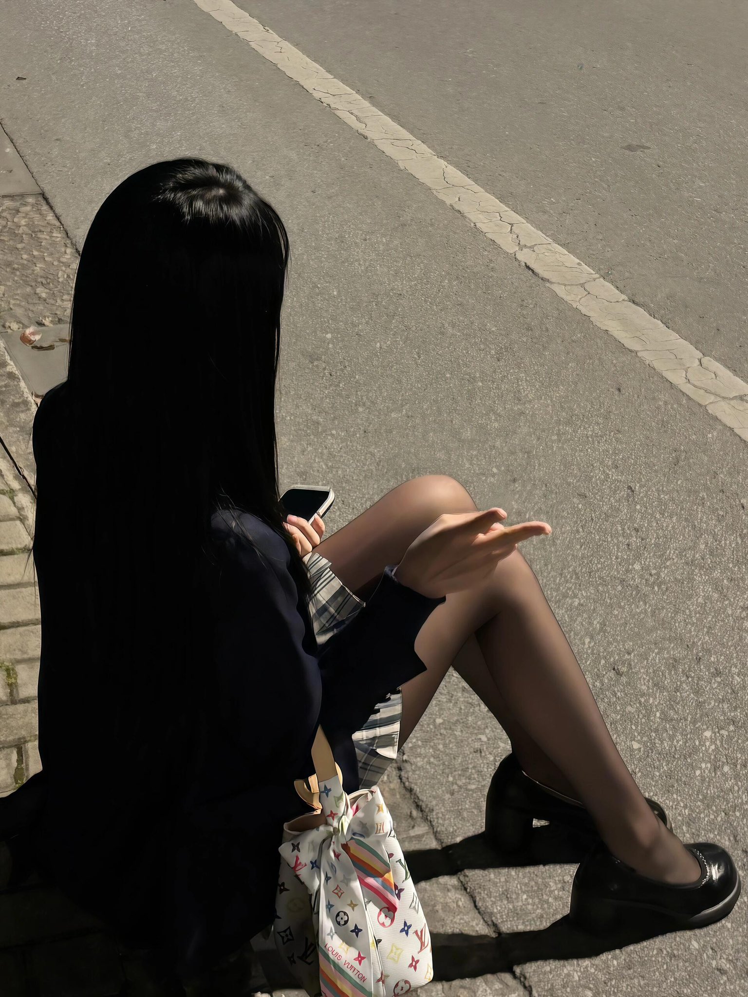 女人坐在街道上,拿着手机。