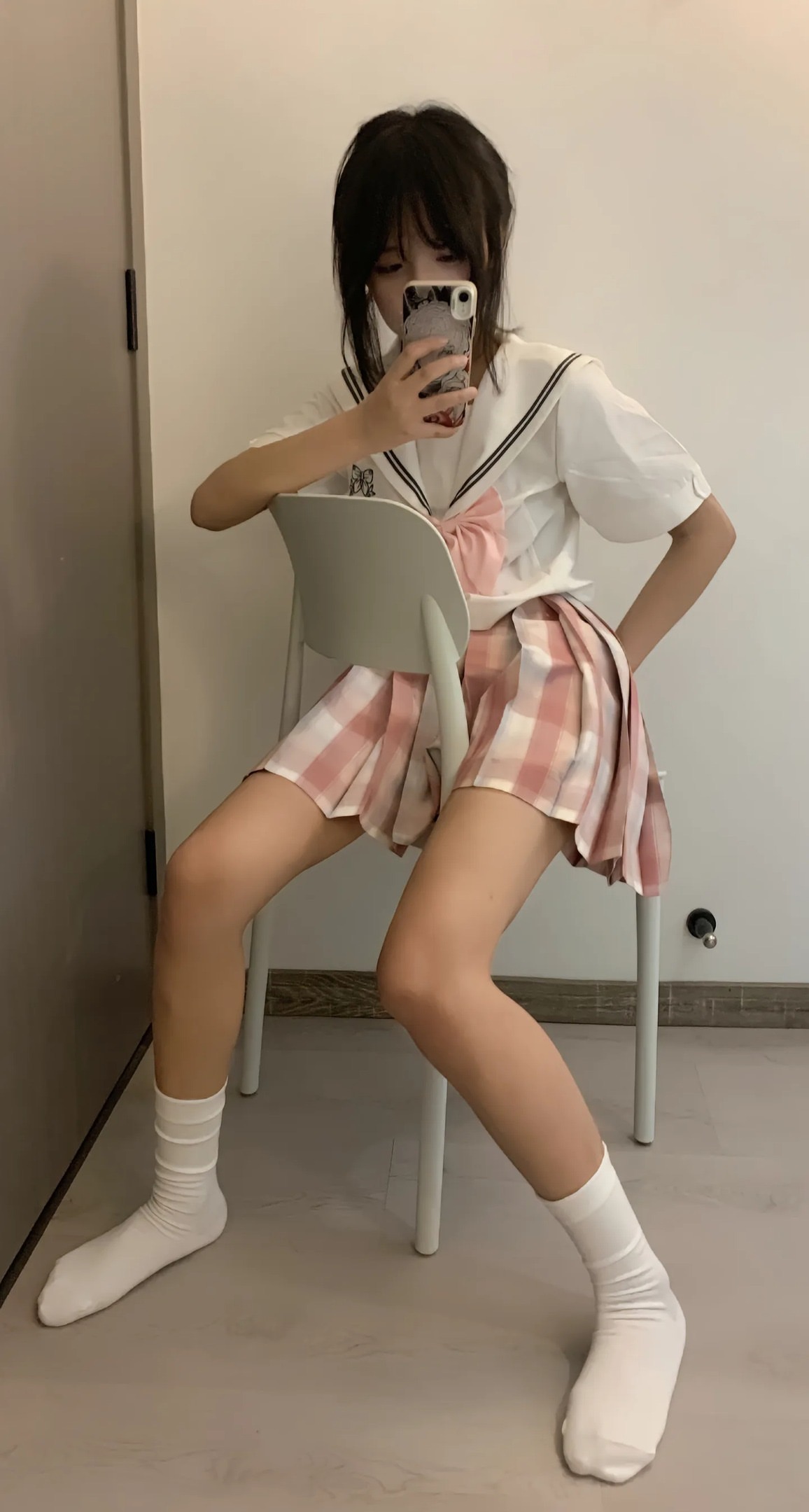 穿白色衬衫和粉红色裙子的女孩坐在椅子上。