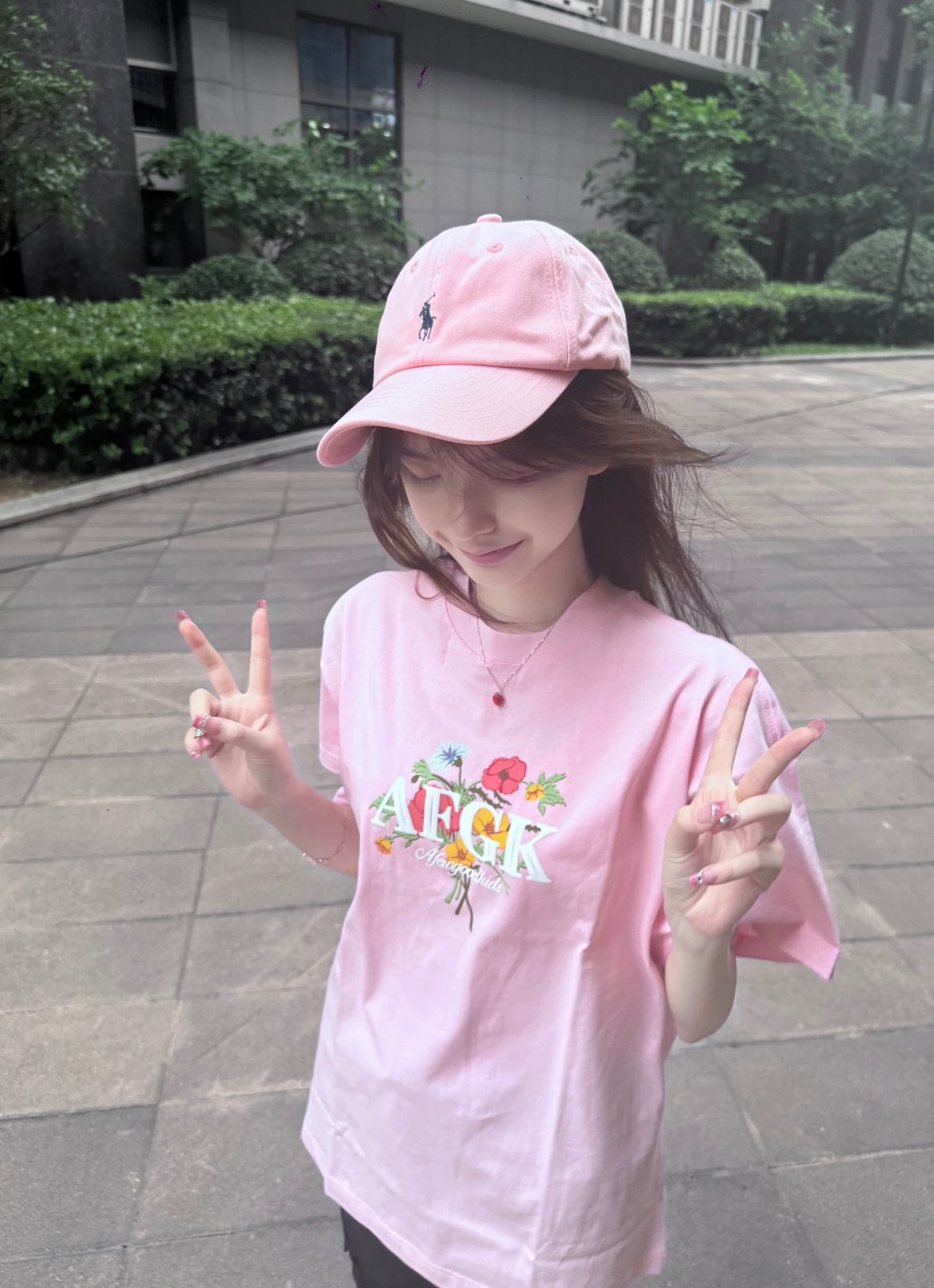 一位穿着粉红色的衬衫和花朵设计的女人站在走廊上。