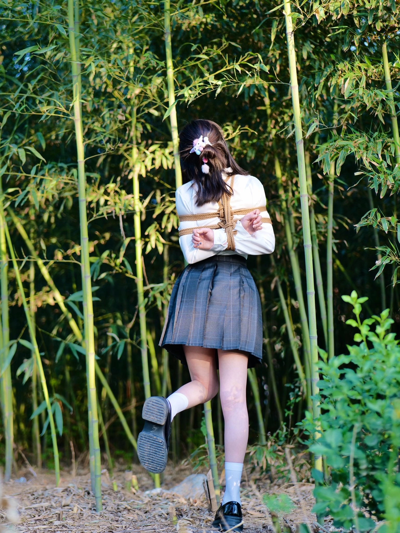 穿着裙子和白衬衫的女人被绳子绑在一起。