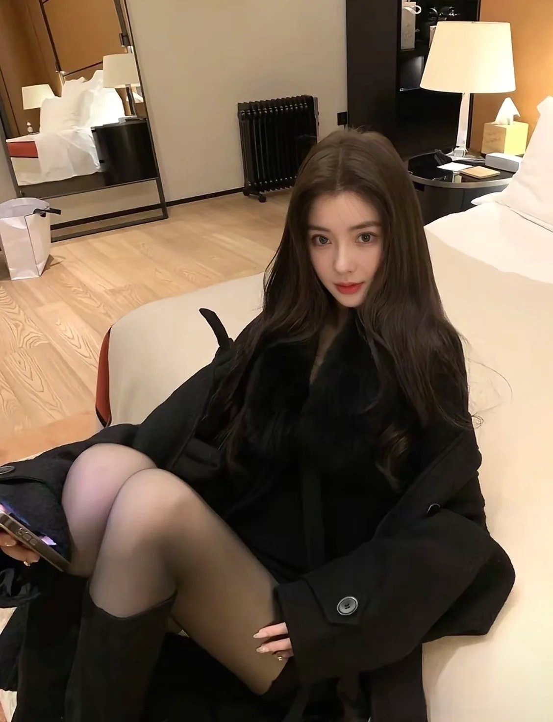 穿着黑色外套的女人坐在床上。