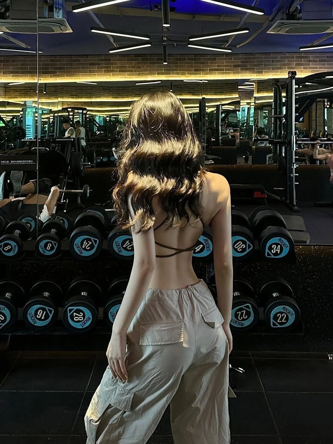 女人在健身房背转。
