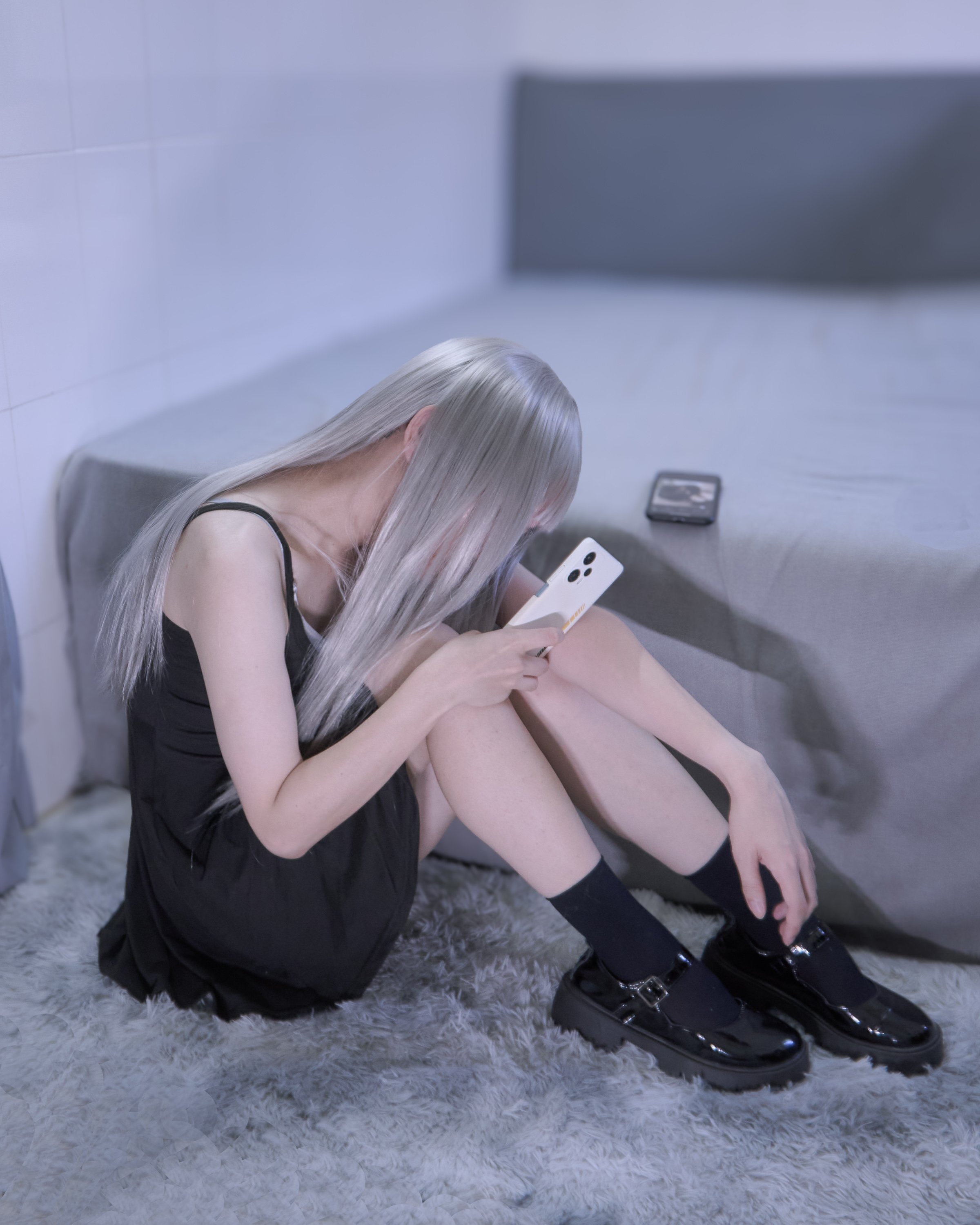 金发的女人坐在床上,看着她的手机。