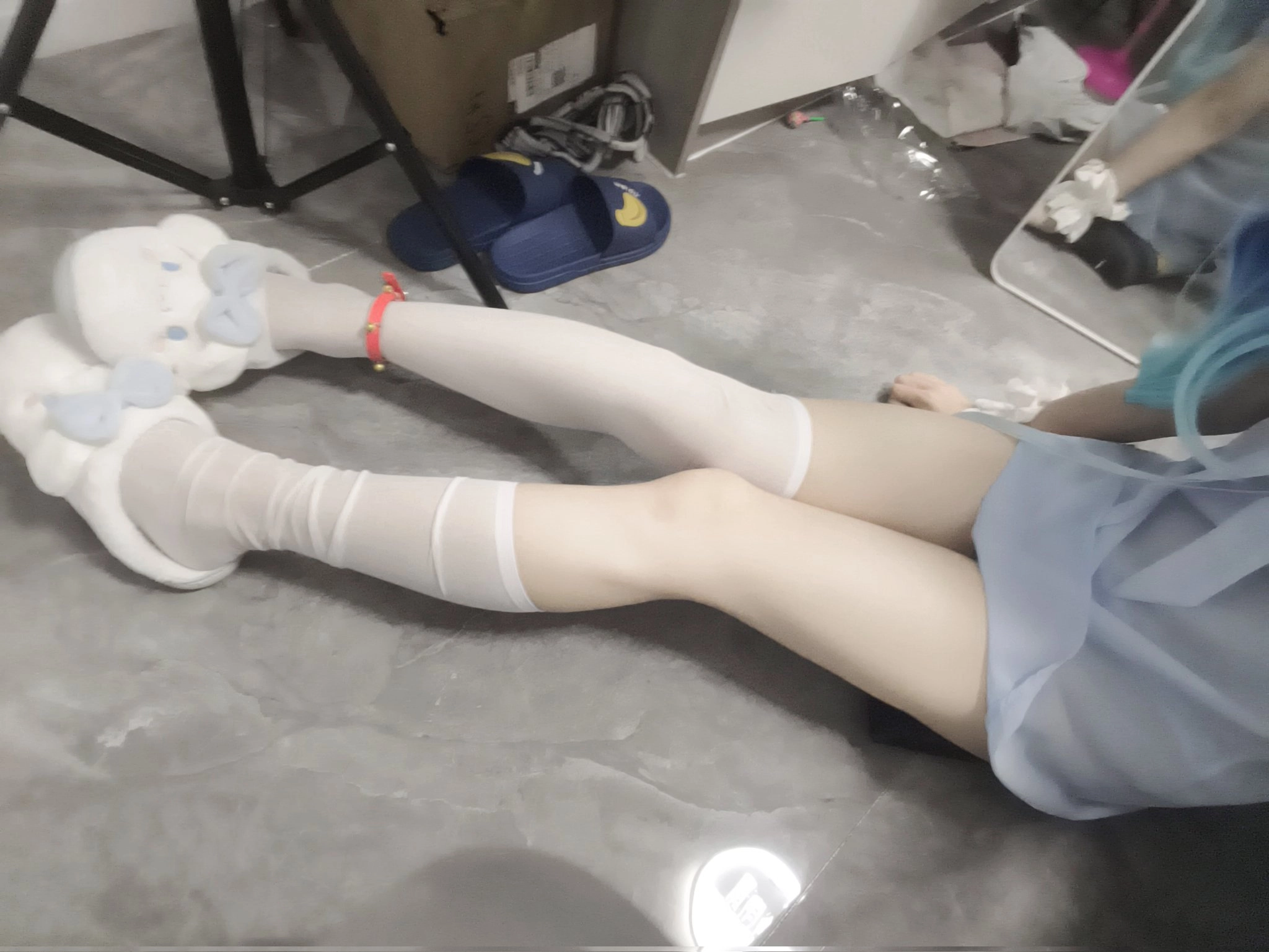 穿着白色袜子和蓝色裙子的人躺在地板上。