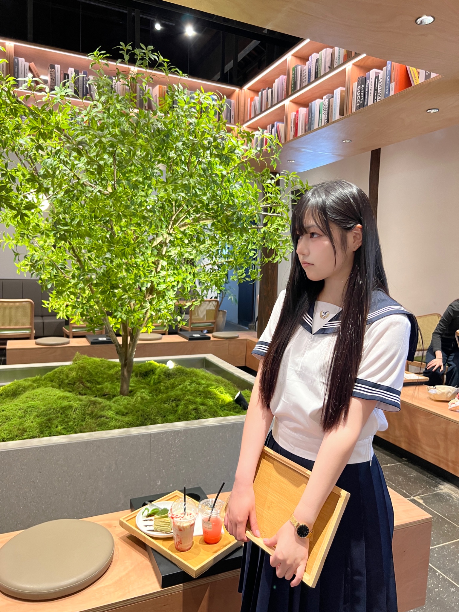 一位穿着白色衬衫和蓝色领带的女人站在一棵树前。