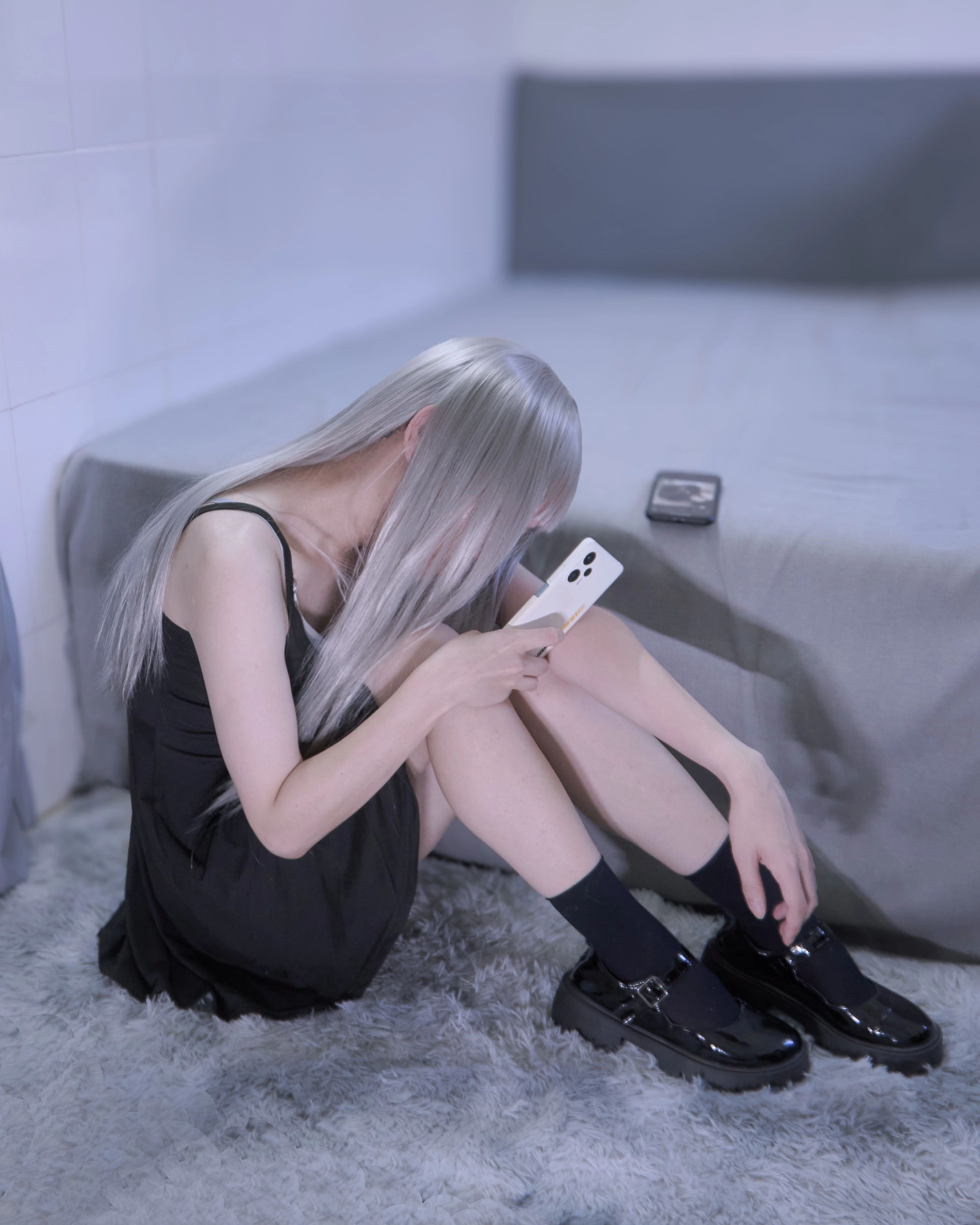 金发的女人坐在床上,看着她的手机。