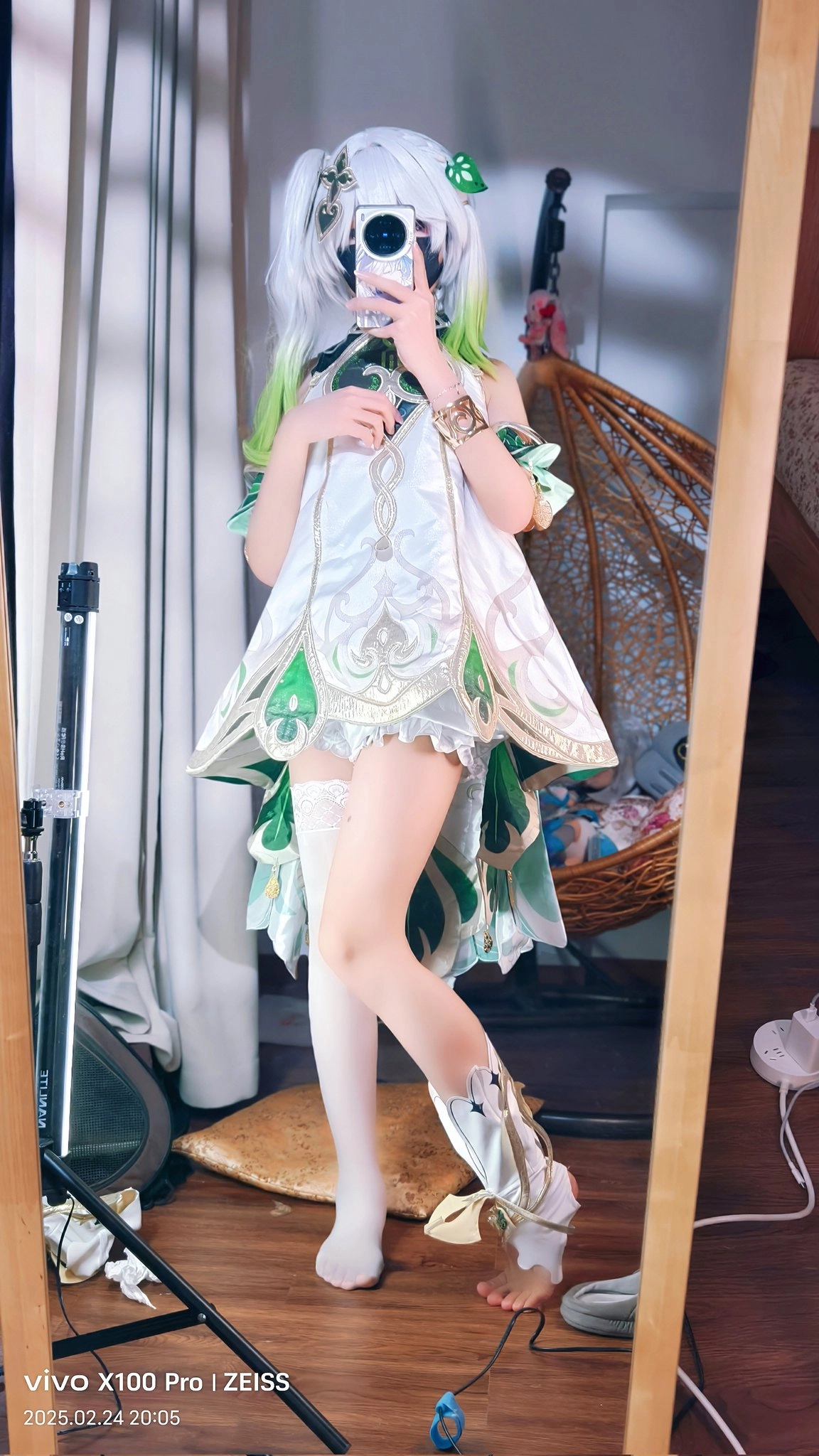 一位穿着绿色的裙子和白色的靴子的女人站在镜子前。