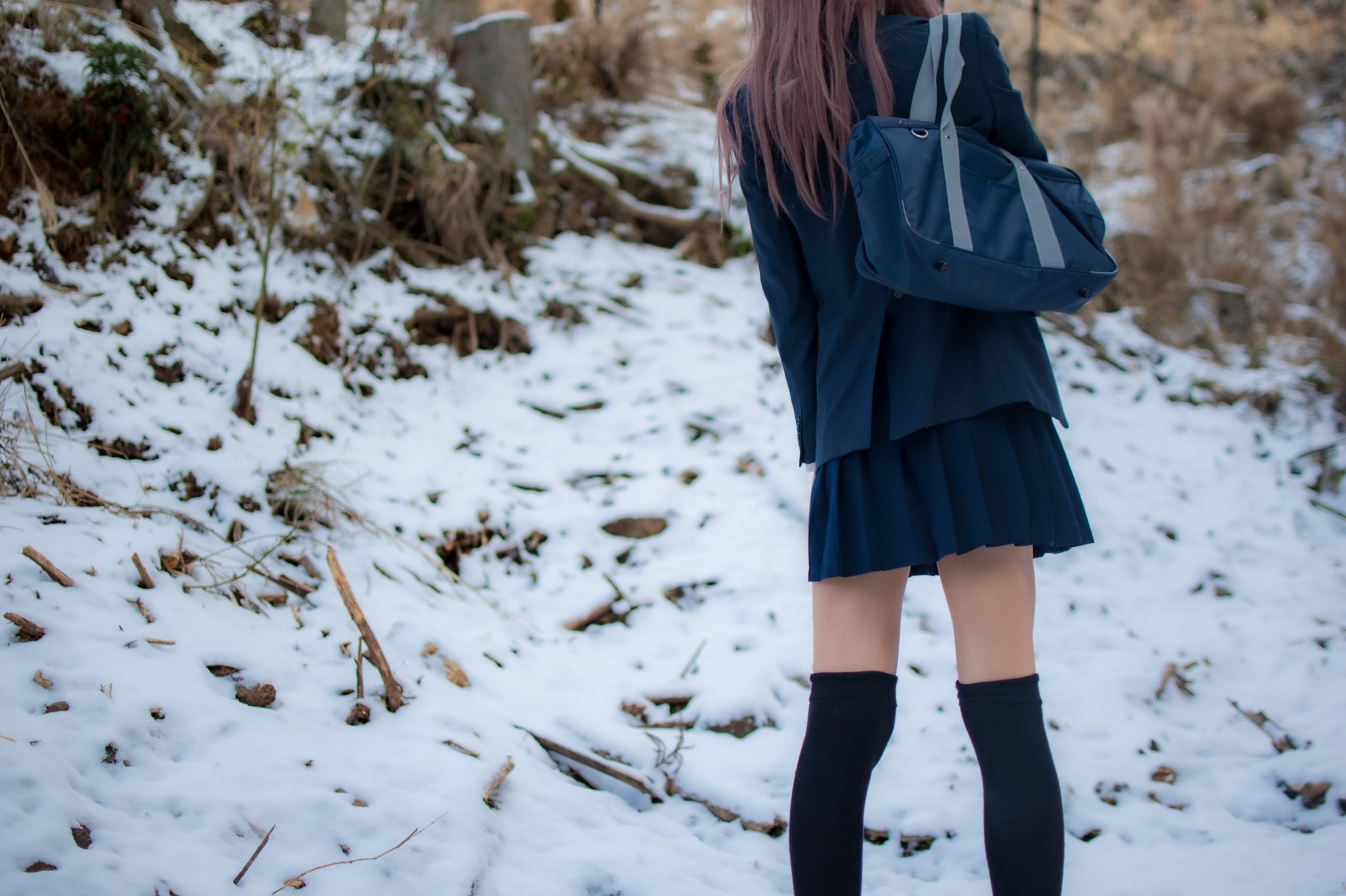 穿着蓝色外套和黑色衬衫的女人站在雪地上。