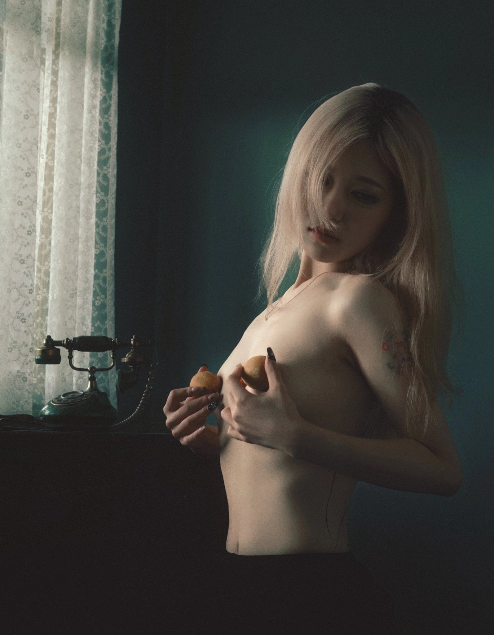 纹身的女人在胸前拿着两个苹果。