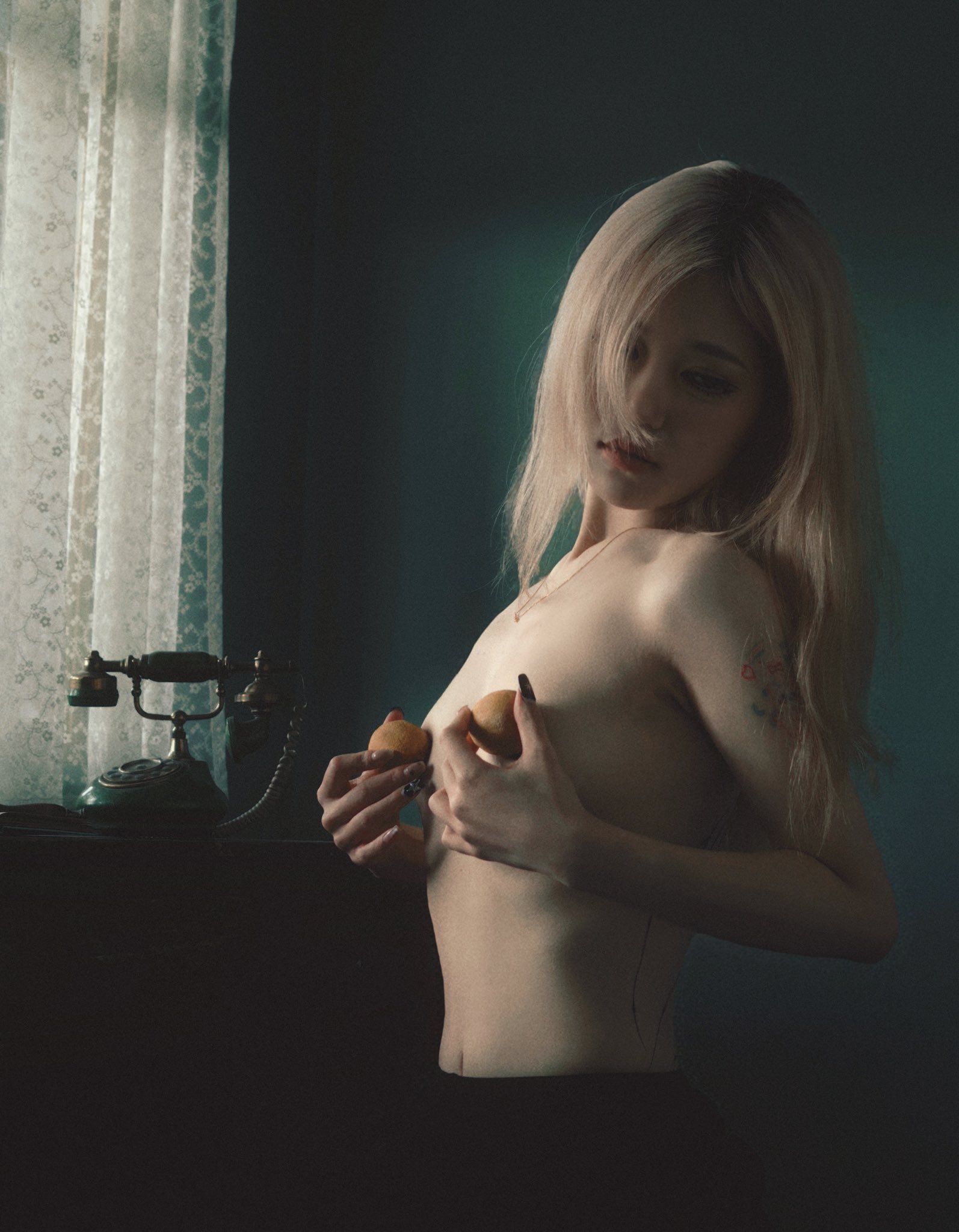 纹身的女人在胸前拿着两个苹果。