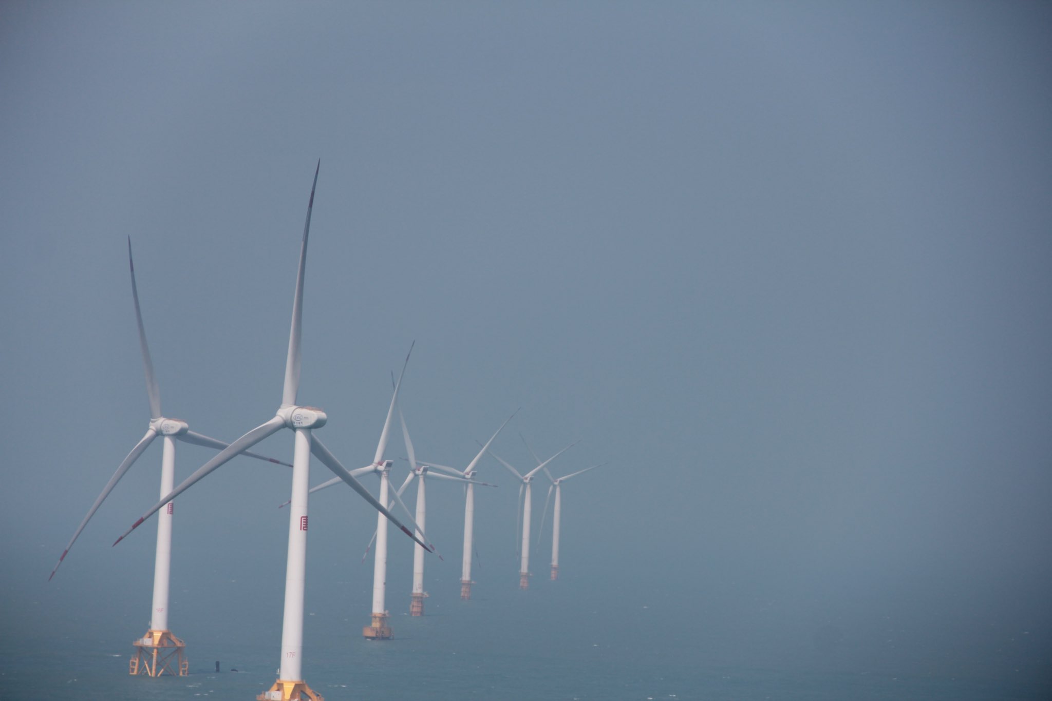 一位黑头发和黑裙子的女人站在一座俯瞰大海的磐石上。