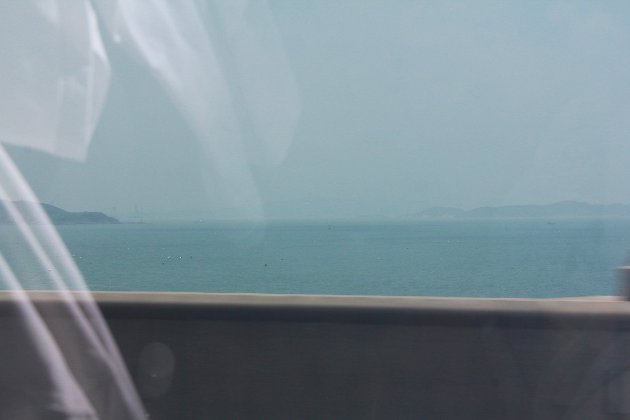 一位黑头发和黑裙子的女人站在一座俯瞰大海的磐石上。