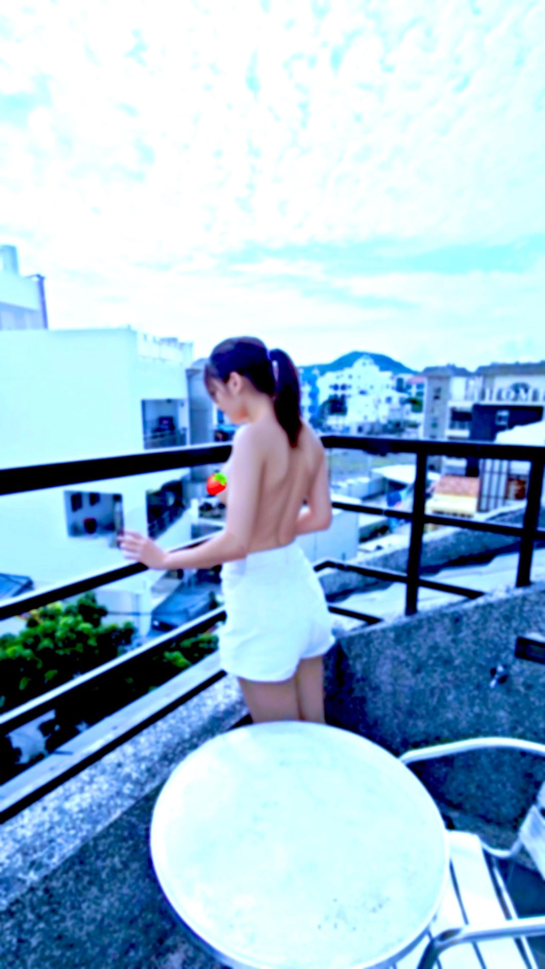 穿着白毛巾的女人站在阳台上。