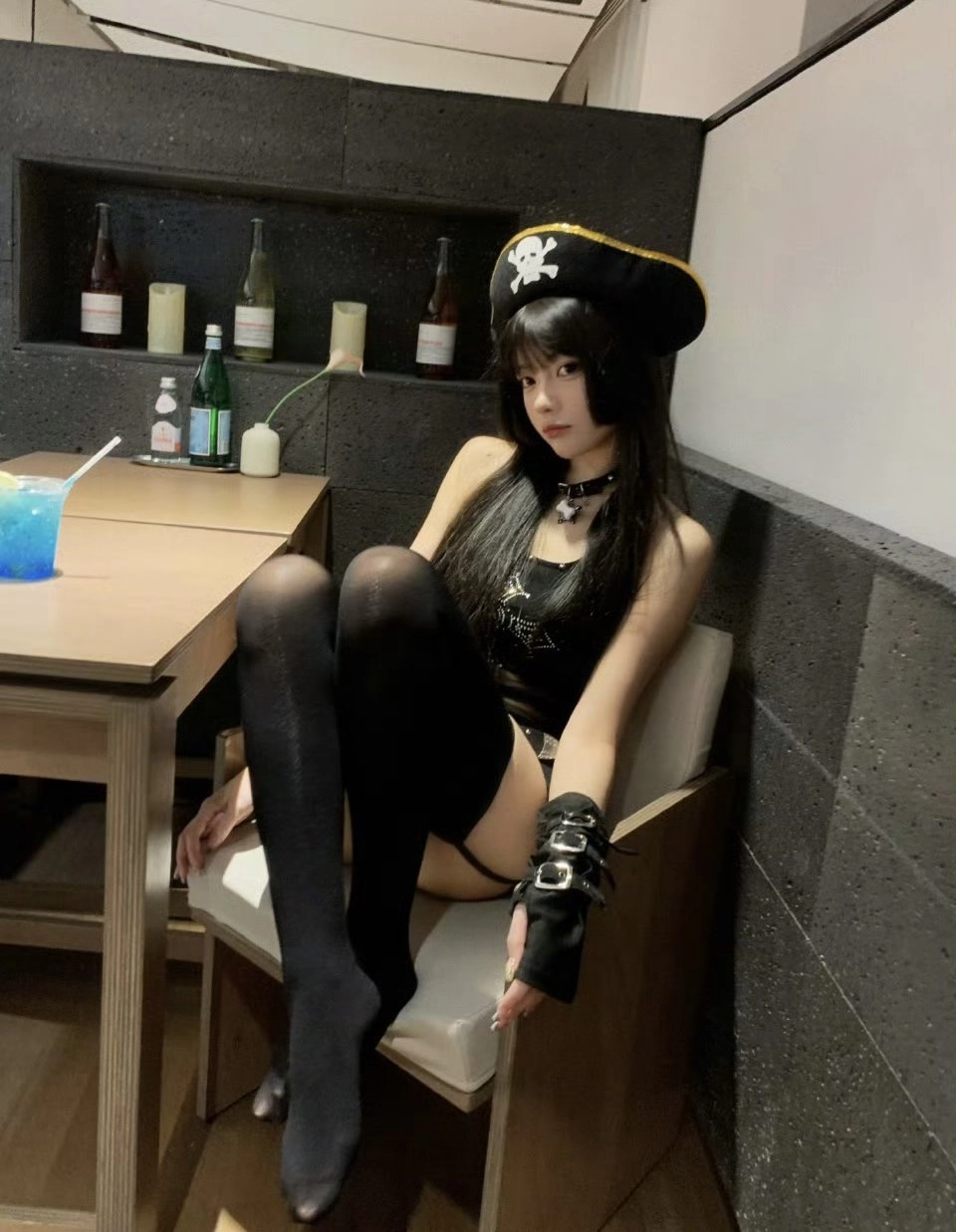 戴着海盗帽子和黑色内衣的女人坐在椅子上。
