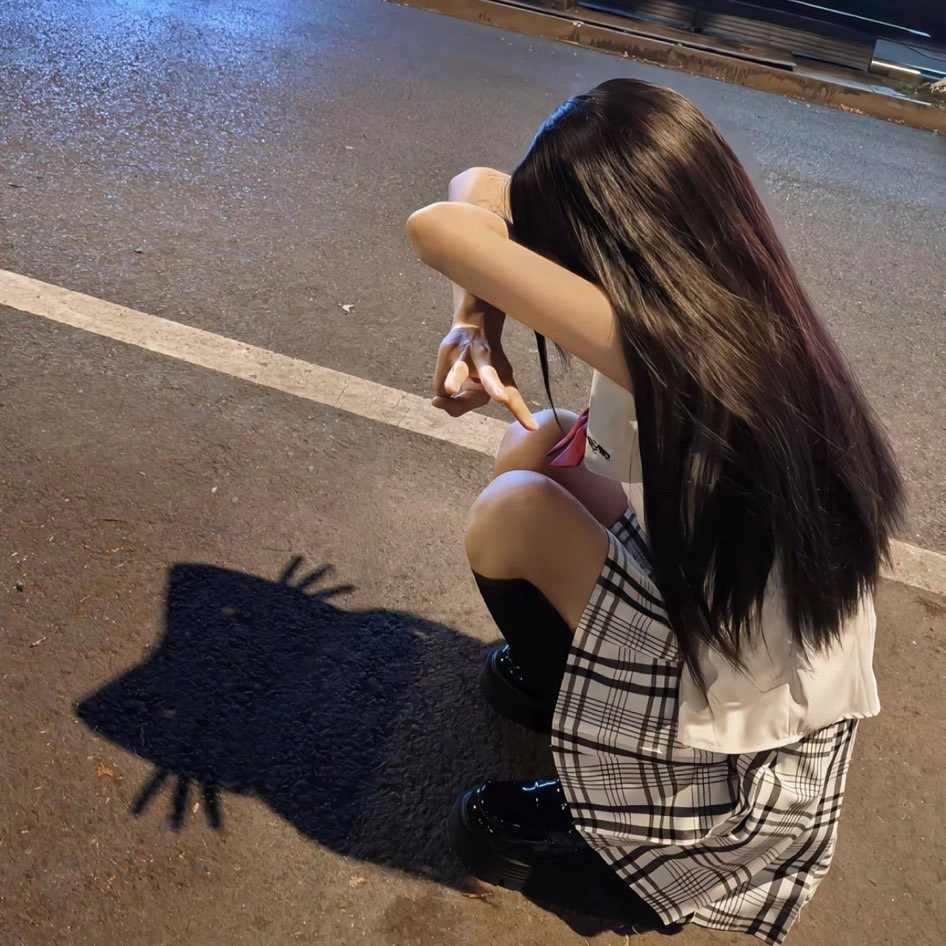 穿着白色衬衫和黑色裙子的女孩跪在地上。