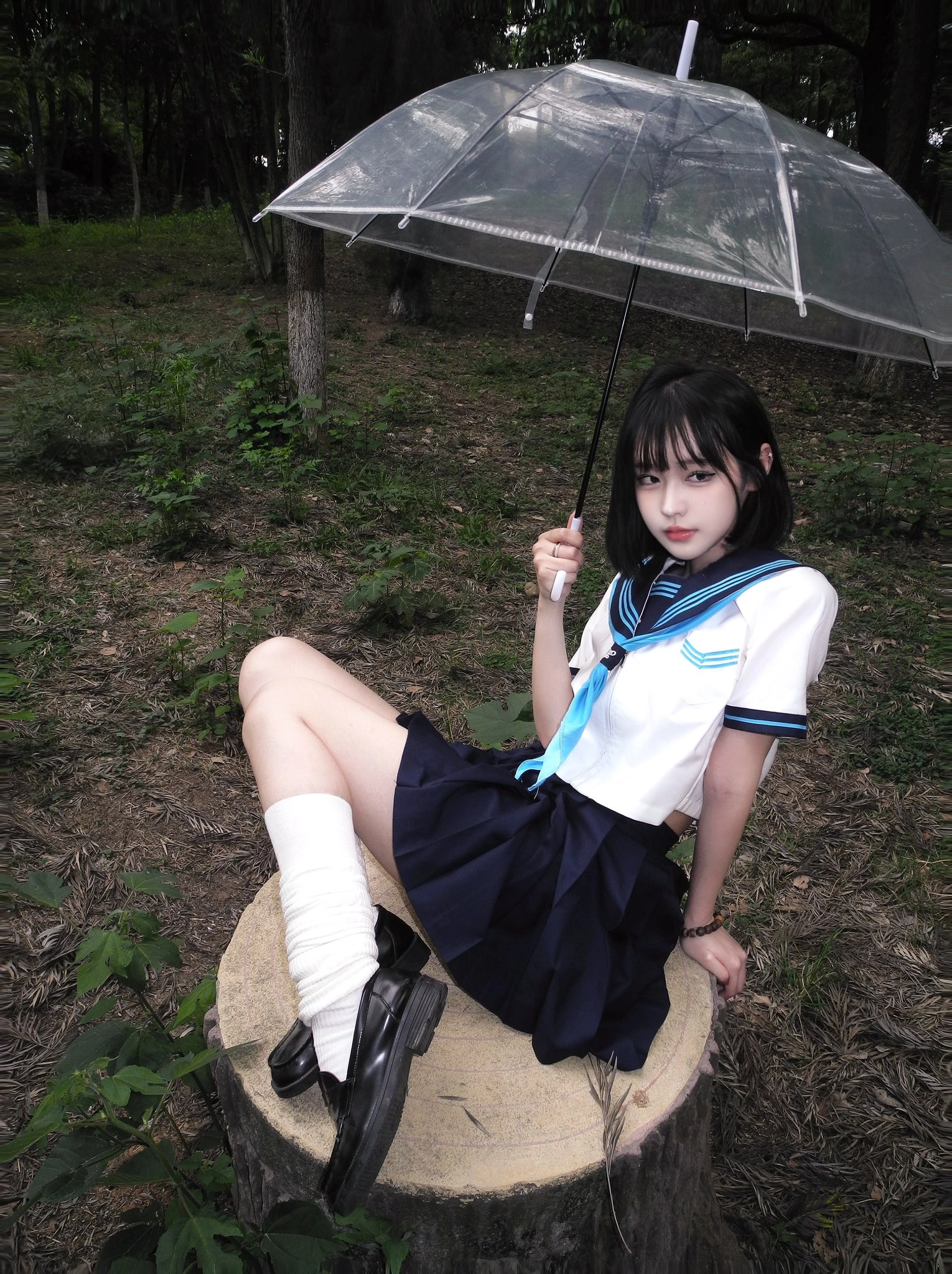 一位穿着白色衬衫和蓝色领带的女人坐在一把伞上。