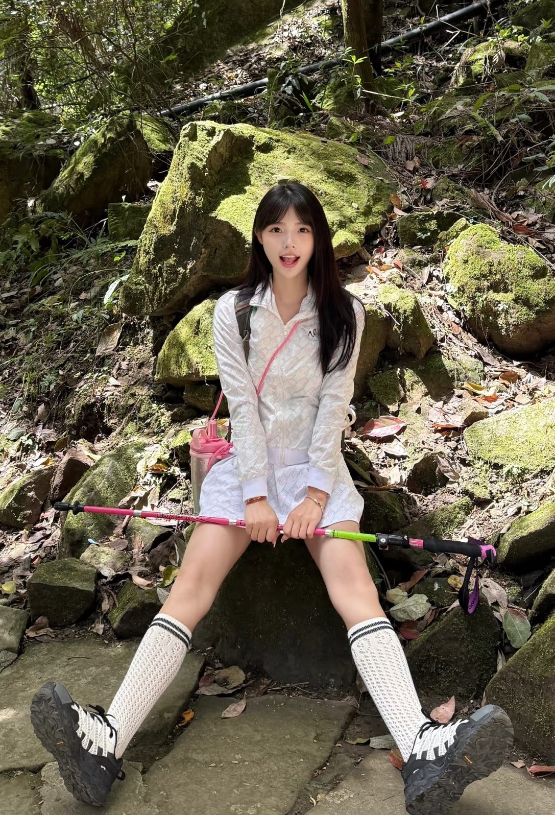 带着粉红色袋子的女人坐在岩石上。