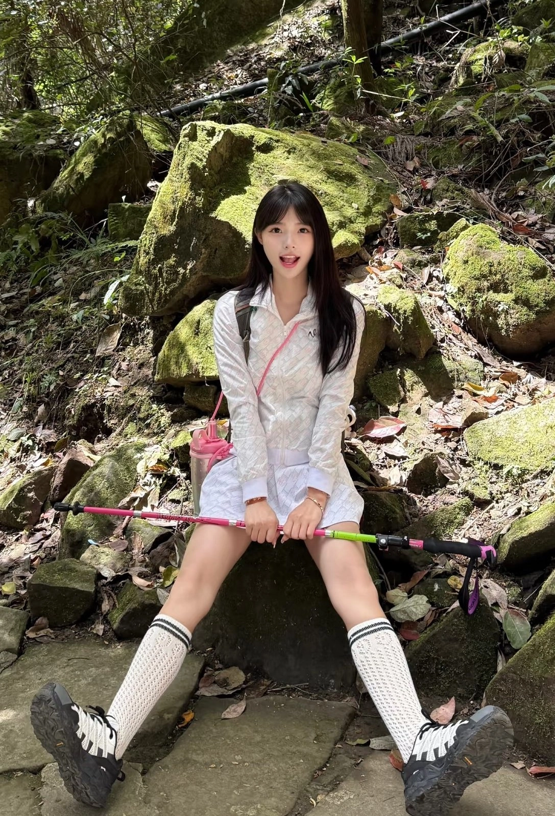 带着粉红色袋子的女人坐在岩石上。