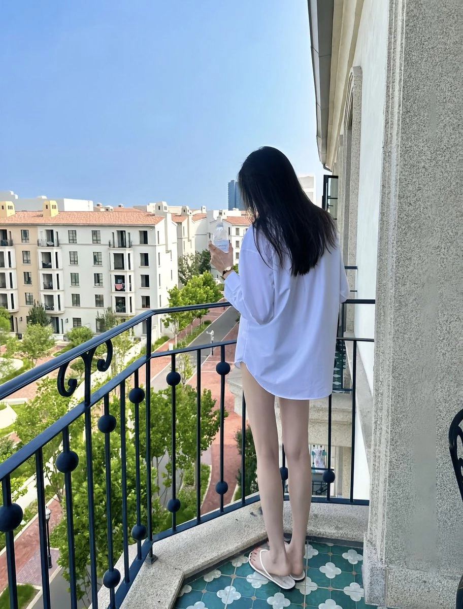 穿着白色衬衫的女人从杯子里喝酒。