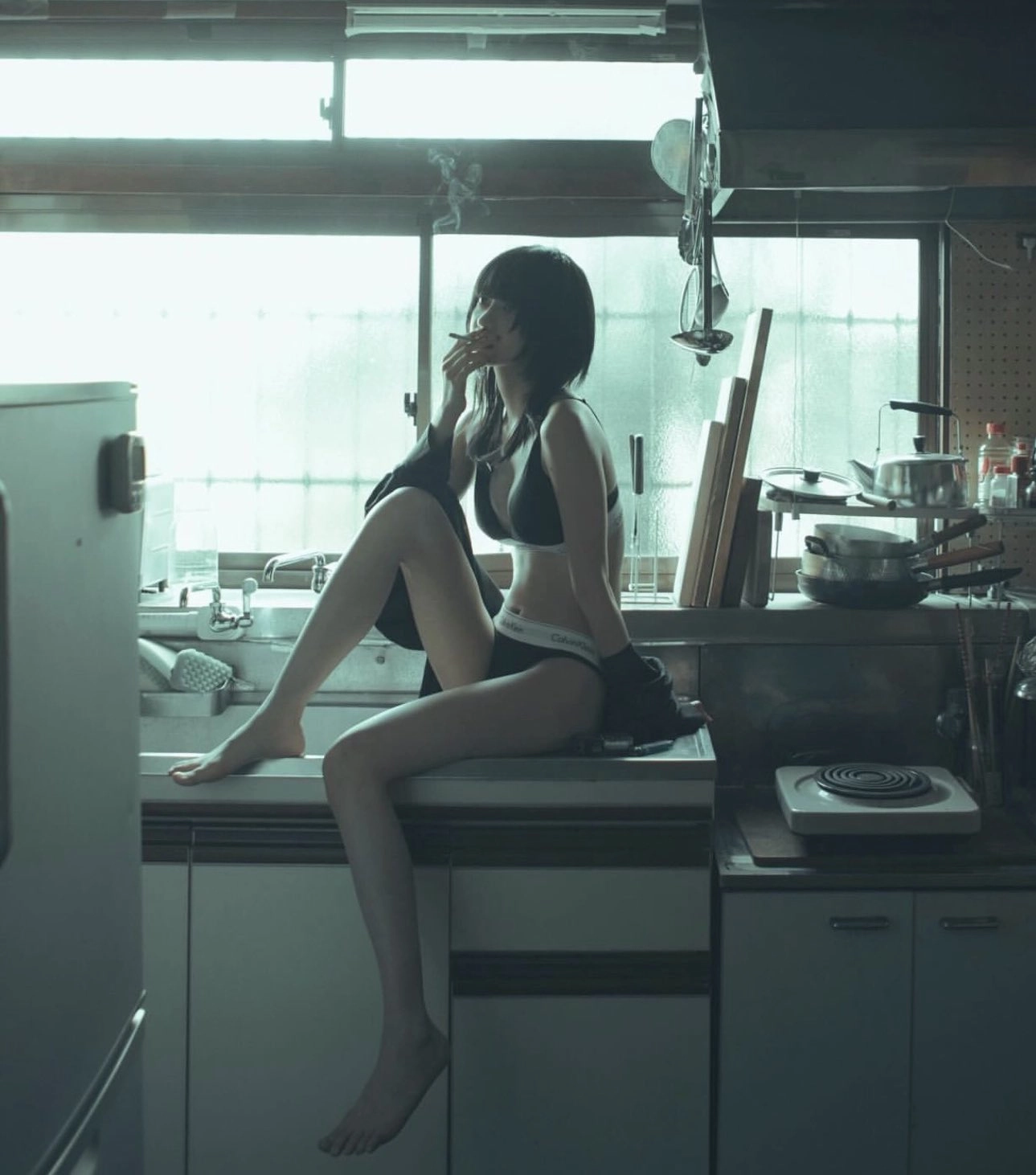 女人在厨房柜子上坐着抽一支烟。