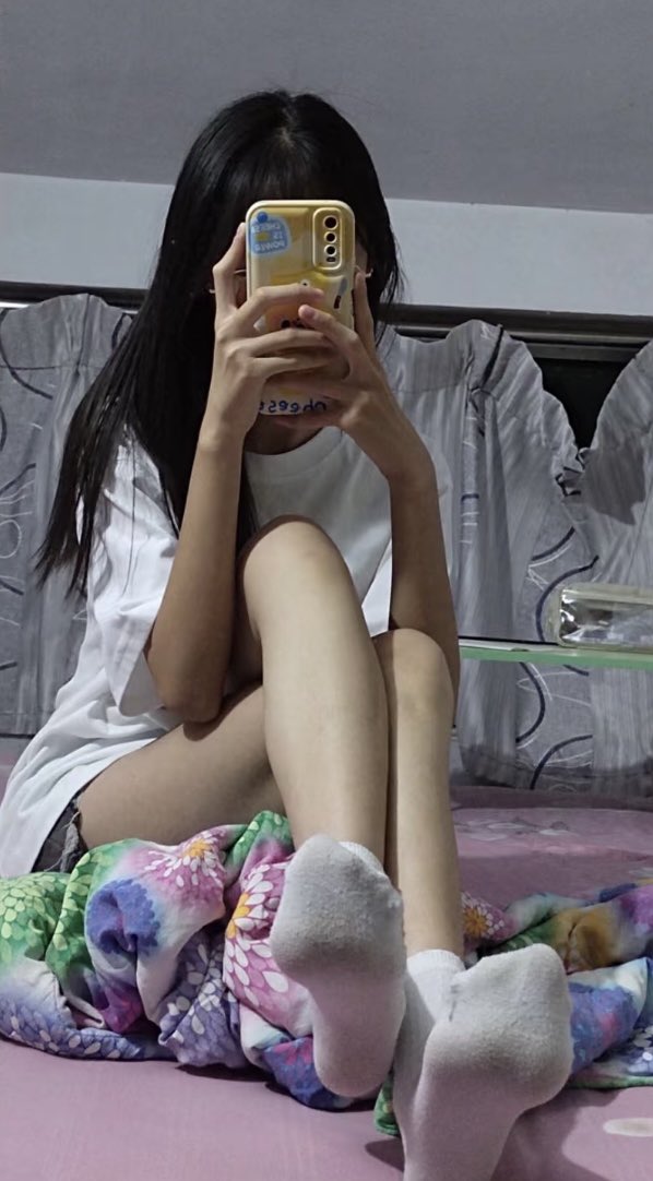 女人坐在床上,拿着手机。