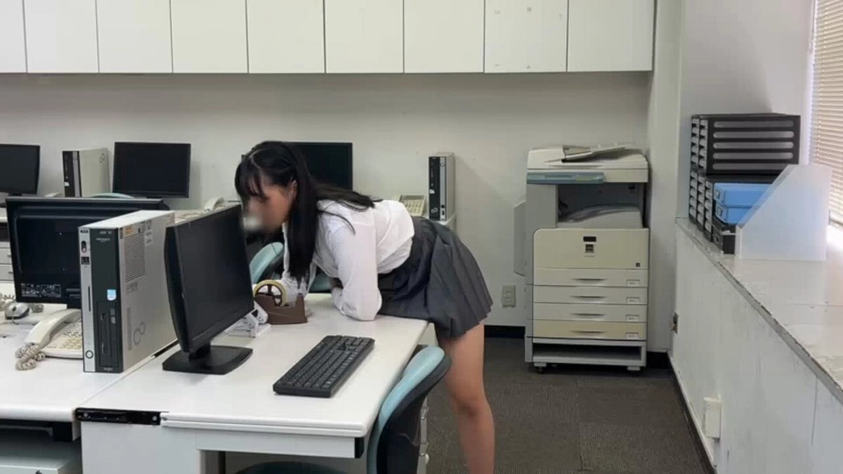 女人躺在一张桌子上,一台电脑键盘和一台电脑监视器。