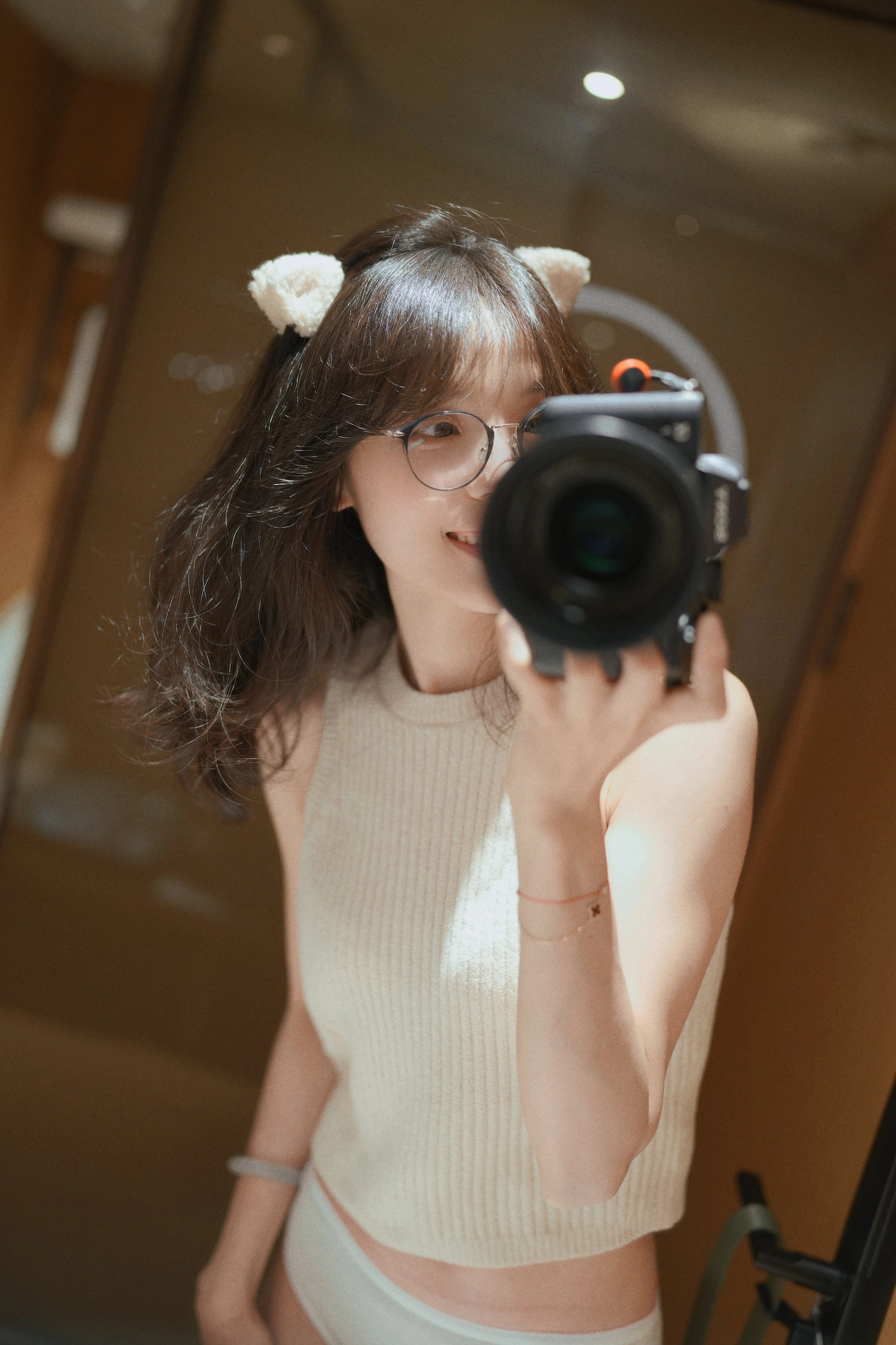 一位戴着眼镜和一件白色衬衫的女人带着相机拍了个自拍。