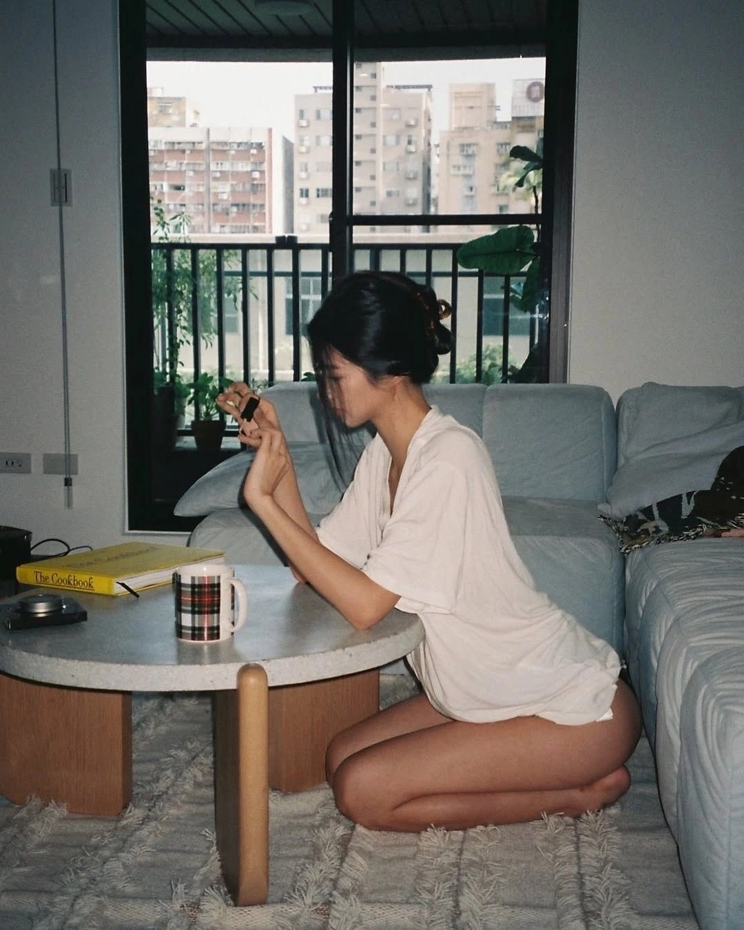 一位穿着白色衬衫的女人坐在一张桌子上,拿着一碗咖啡。