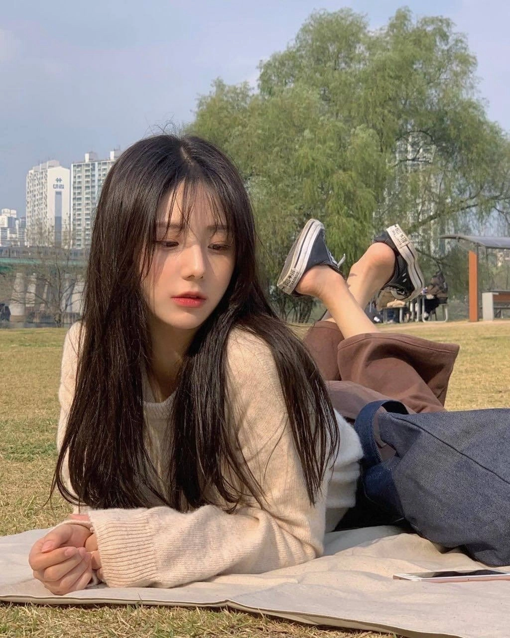 穿着白色衬衫和黑色鞋子的女人躺在草地上。