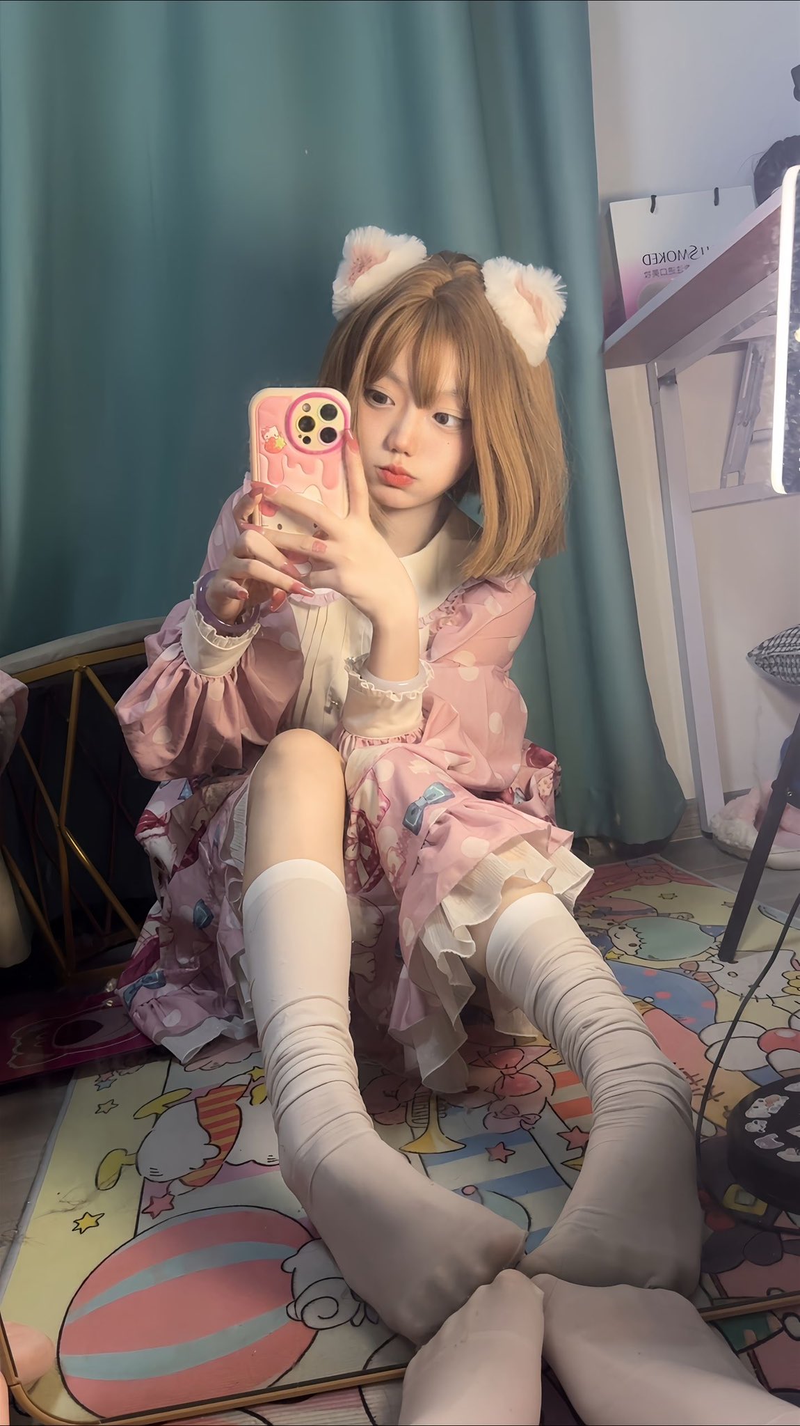 穿着粉红色衣服的女孩正在用粉红色的手机拍照。