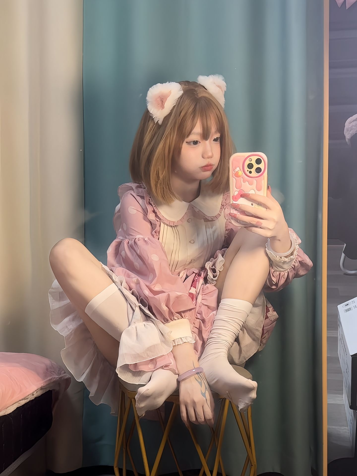 穿着粉红色衣服的女孩正在用粉红色的手机拍照。