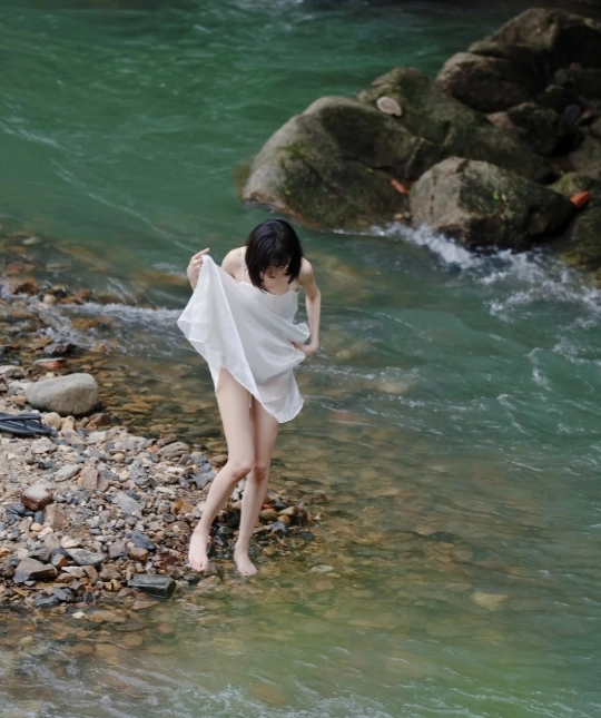 穿着白叶子的女人穿过一条河流。