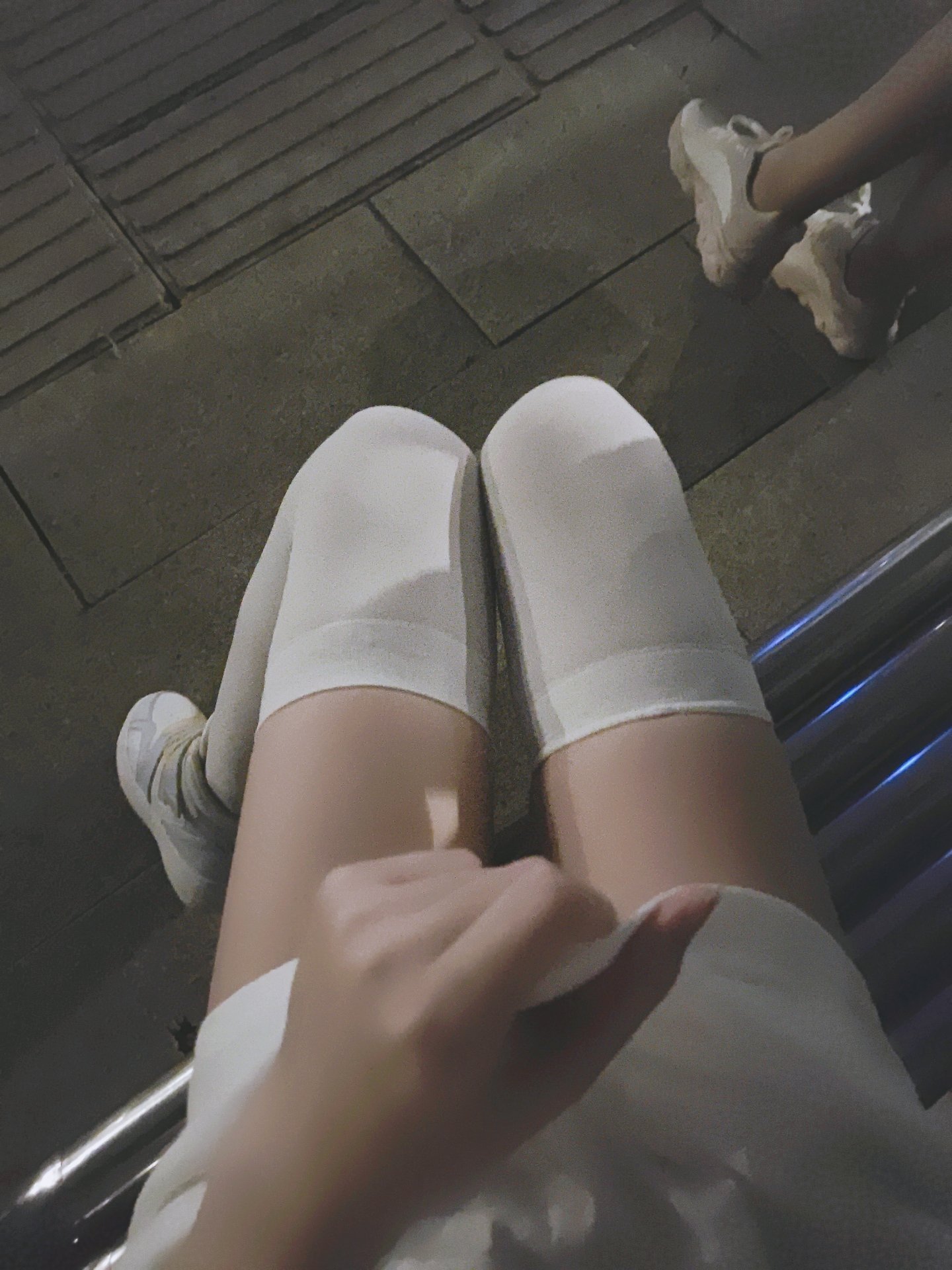 穿着白色袜子和白色的鞋子的女人坐在一个凳子上。