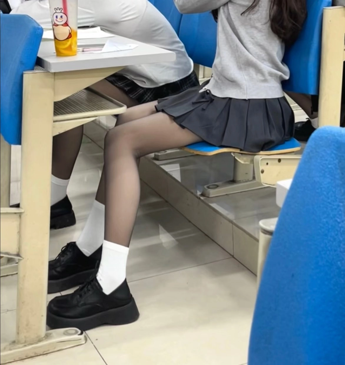 穿着灰色衬衫和黑色衬衫的女孩坐在椅子上。